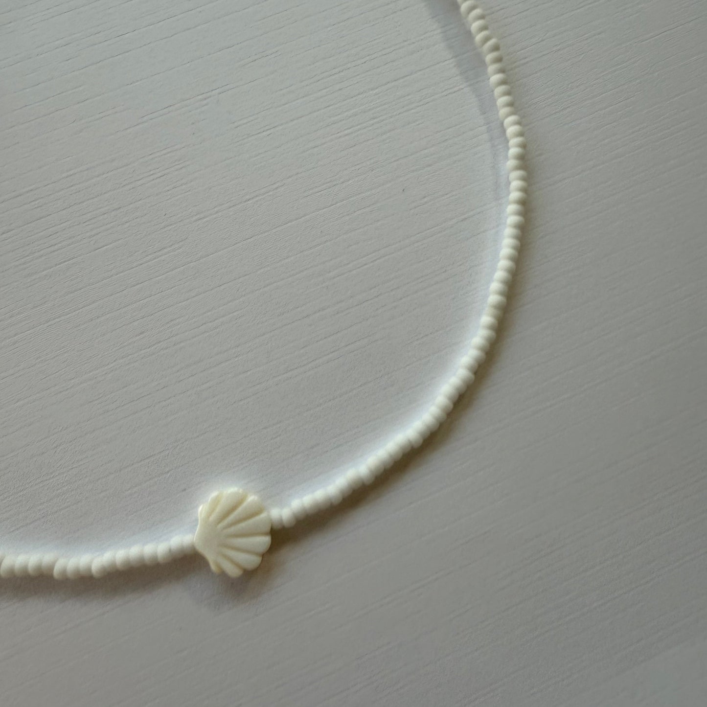 White shell-shaped hair tie on a light gray background