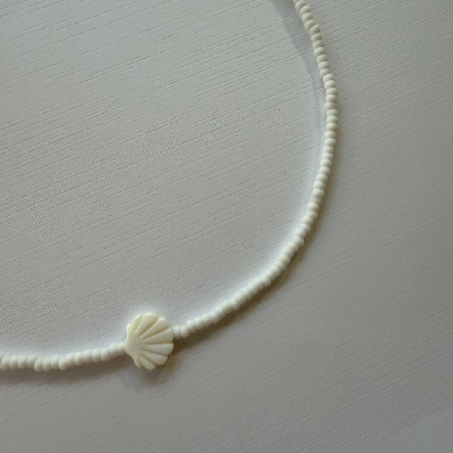 White shell-shaped hair tie on a light gray background