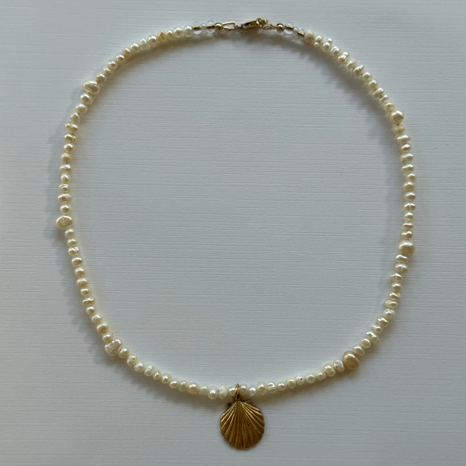 Pearl necklace with a gold clasp on a light gray background