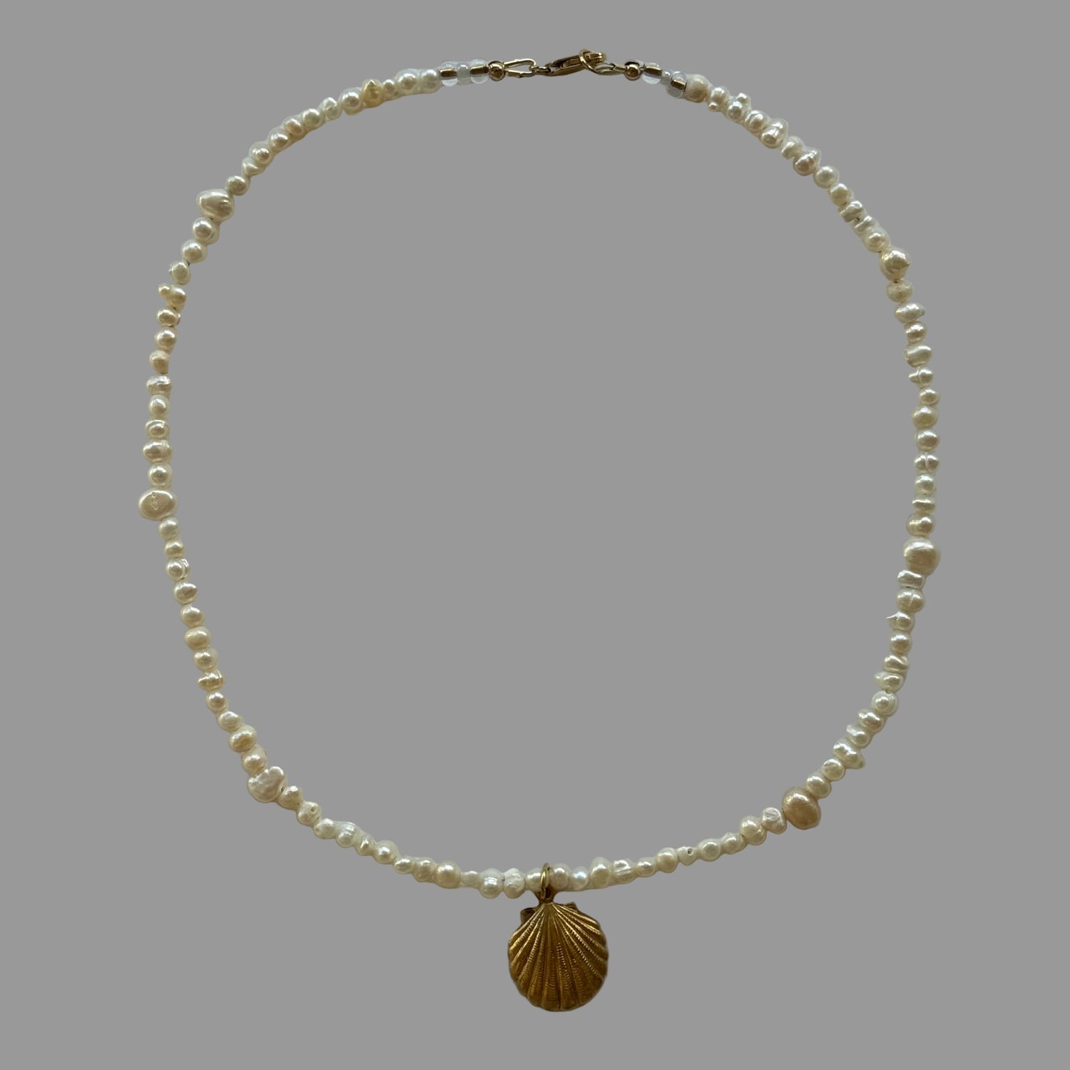 Pearl necklace with a gold clasp on a light gray background
