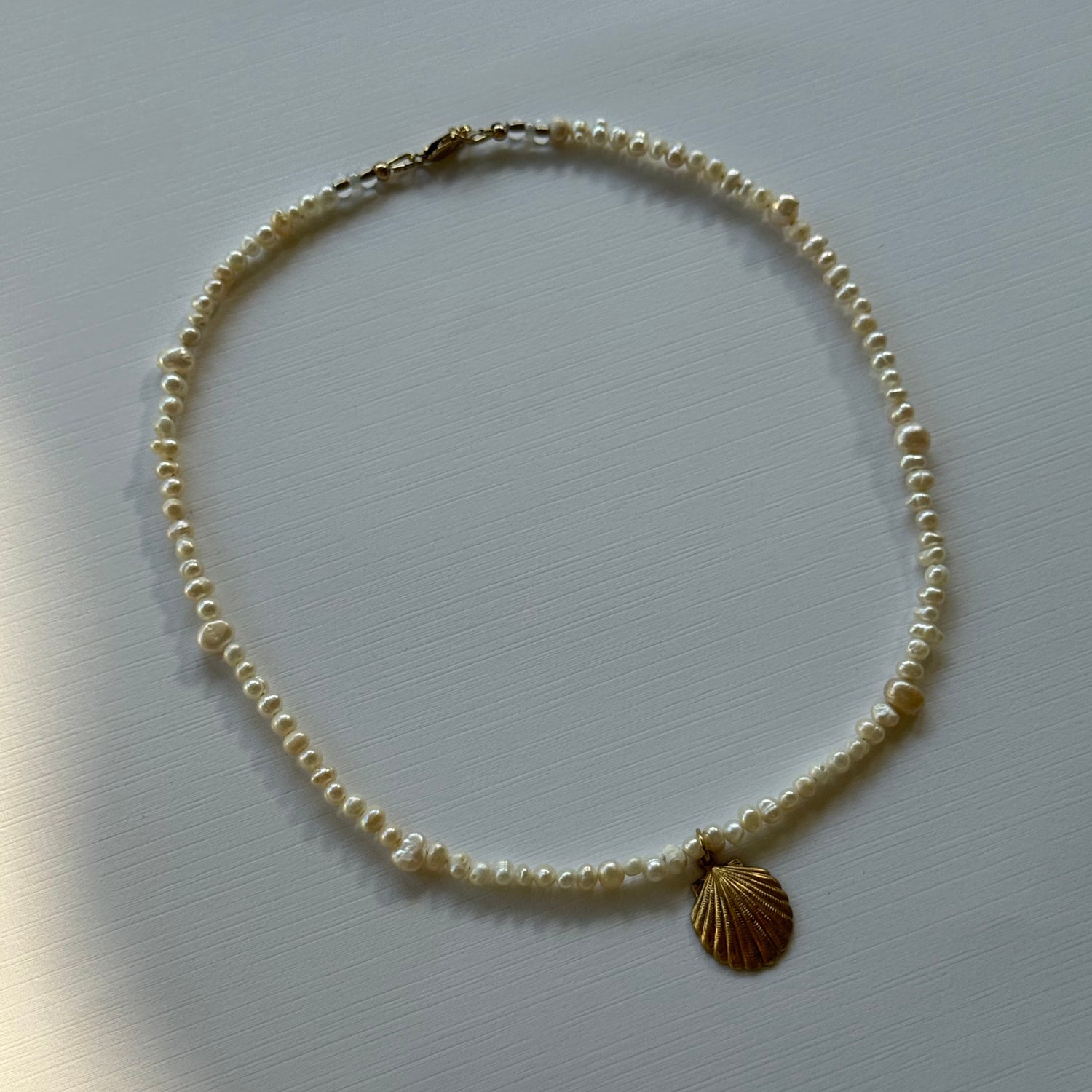 Pearl necklace with a gold clasp on a light gray background