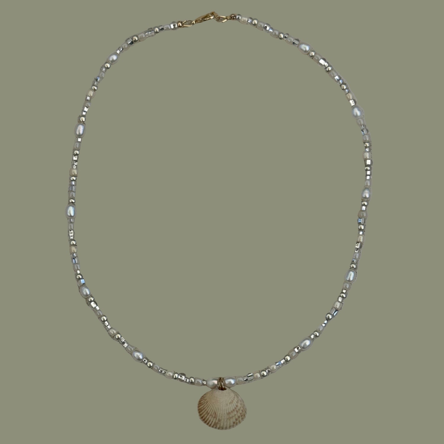 Silver beaded necklace on a textured beige background
