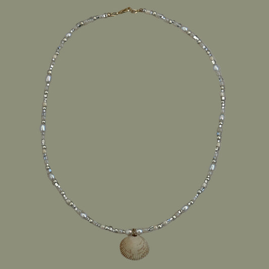 Silver beaded necklace on a textured beige background