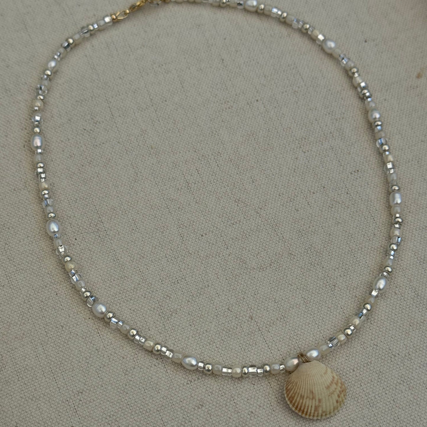 Beaded necklace with a shell on a beige surface