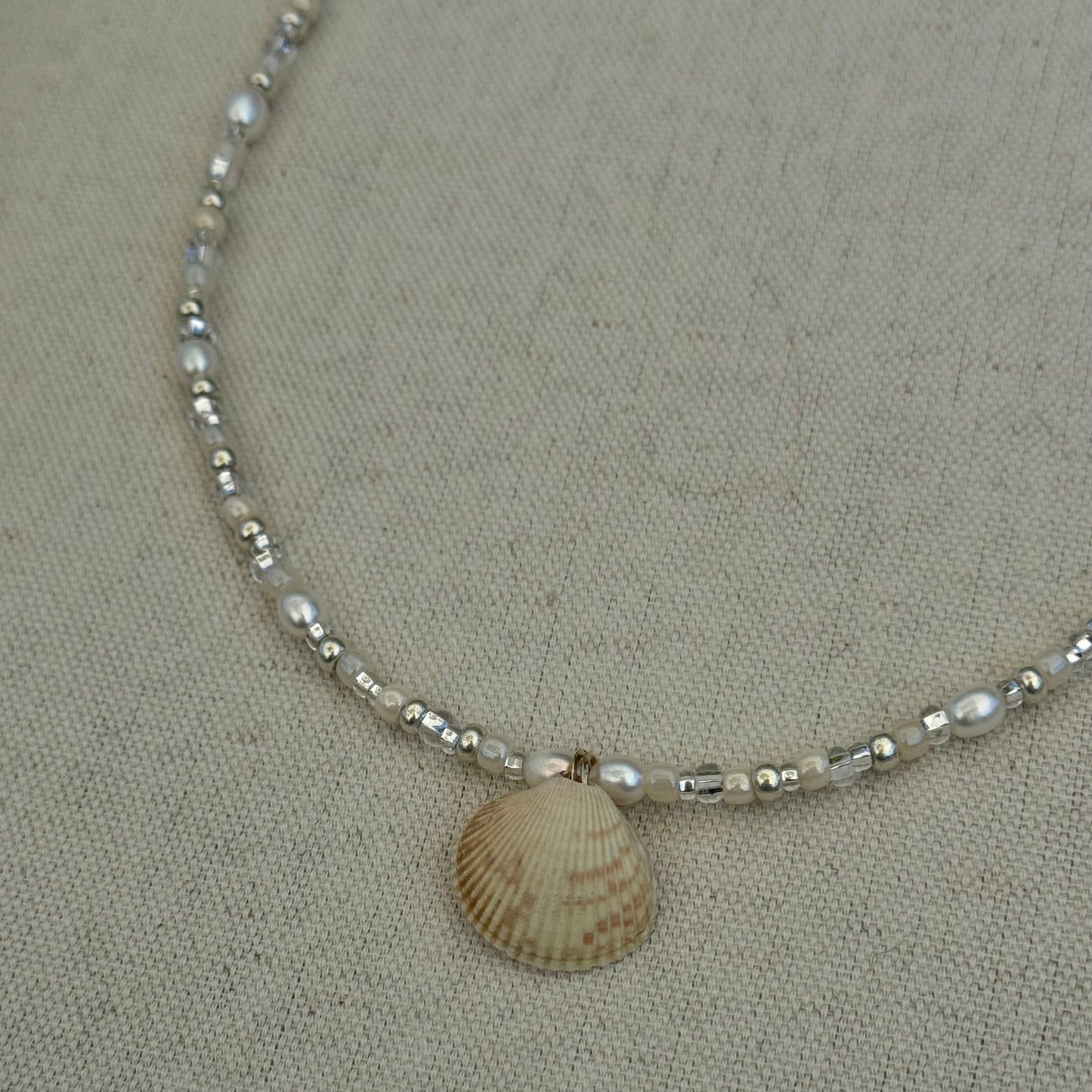 Necklace with shell pendant on a beige fabric background