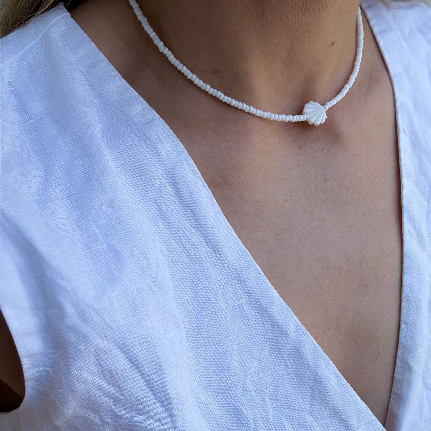 Necklace with a knot pendant on a person wearing a white shirt.