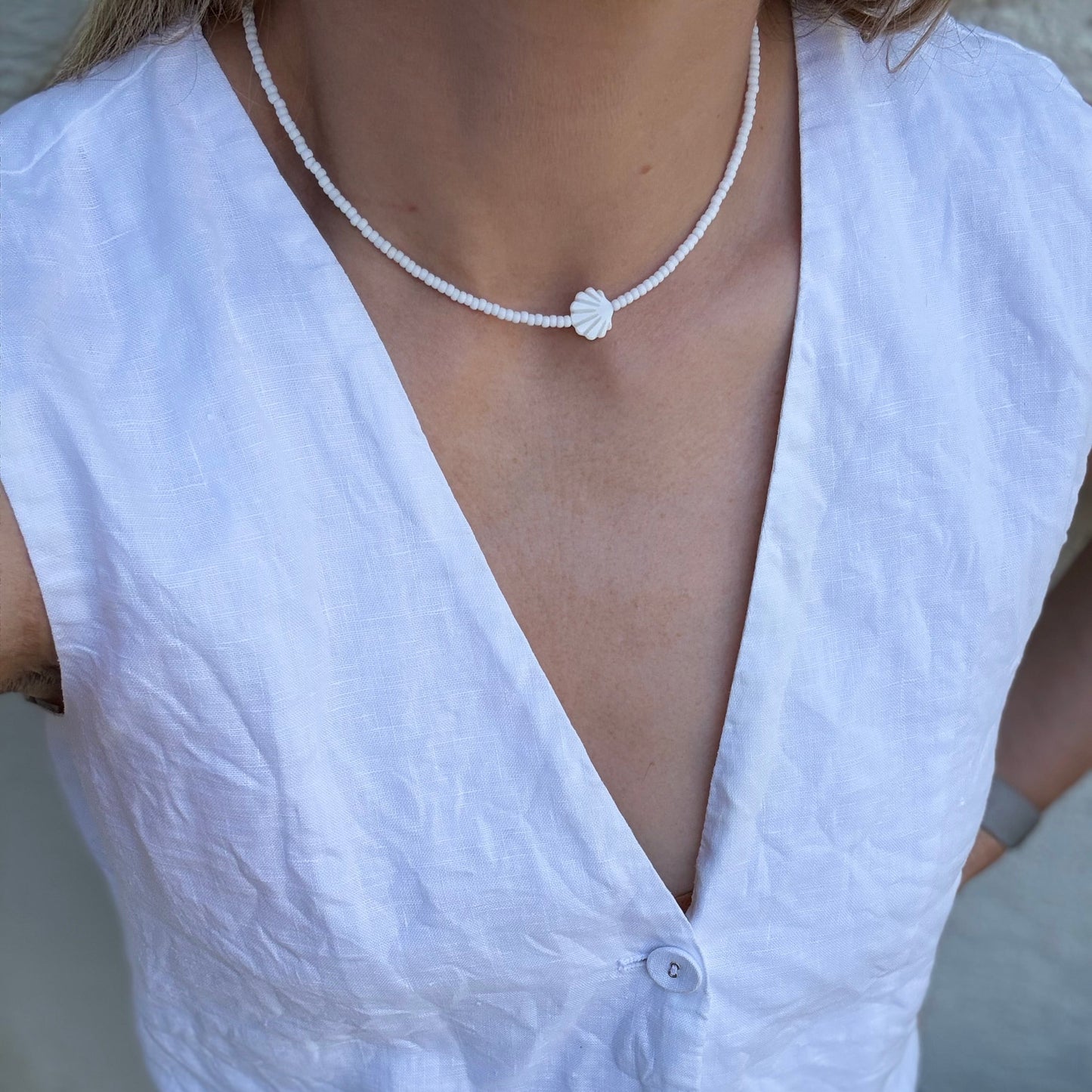 White sleeveless top worn by a person with a necklace.