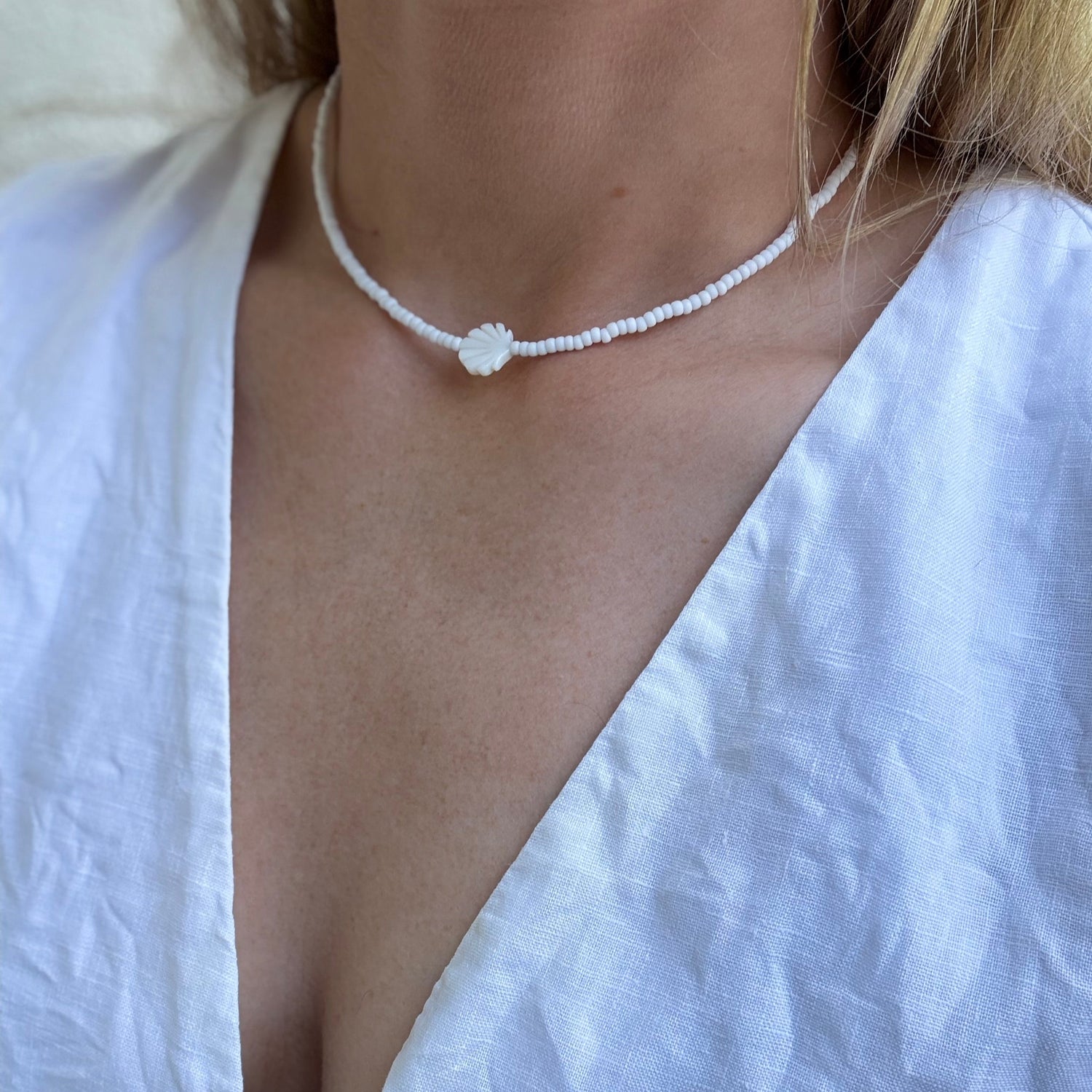Person wearing a delicate necklace with a white top