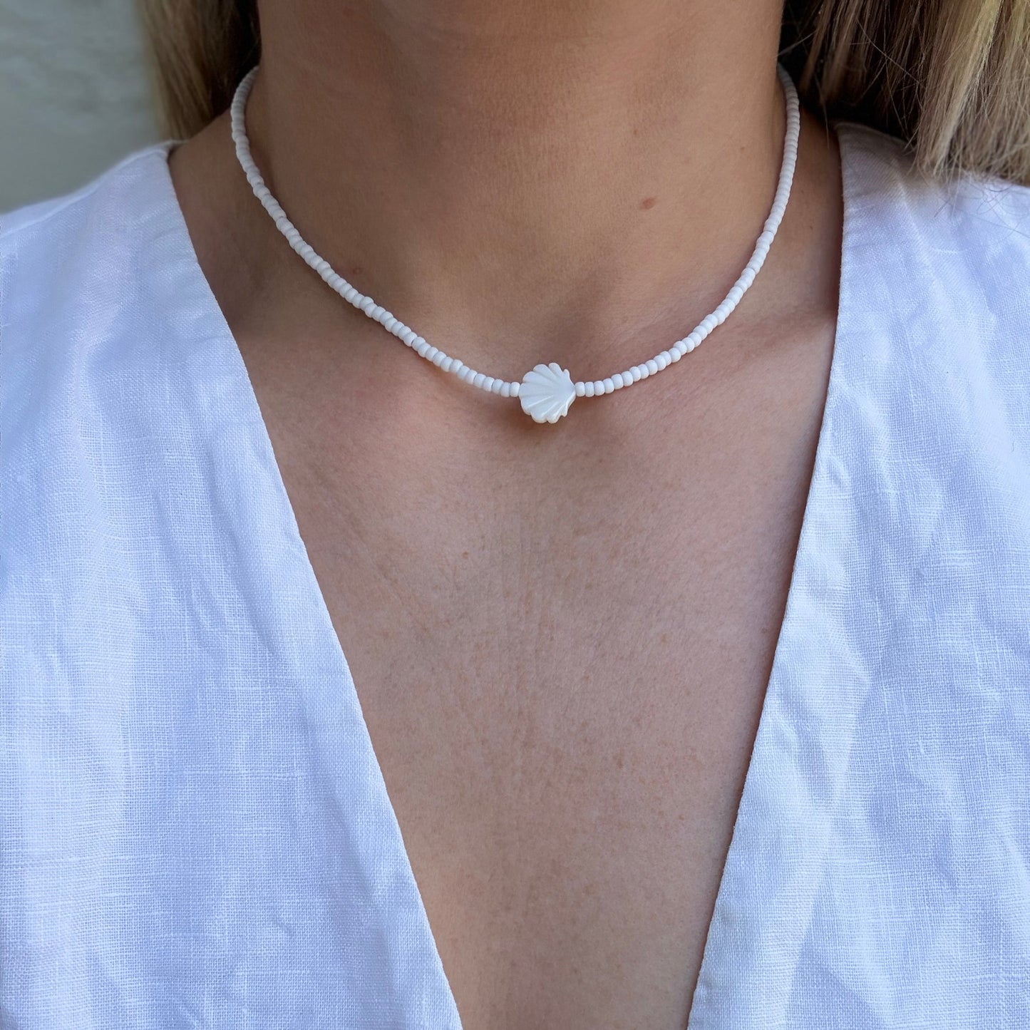 Necklace with a floral pendant worn by a person in a white top