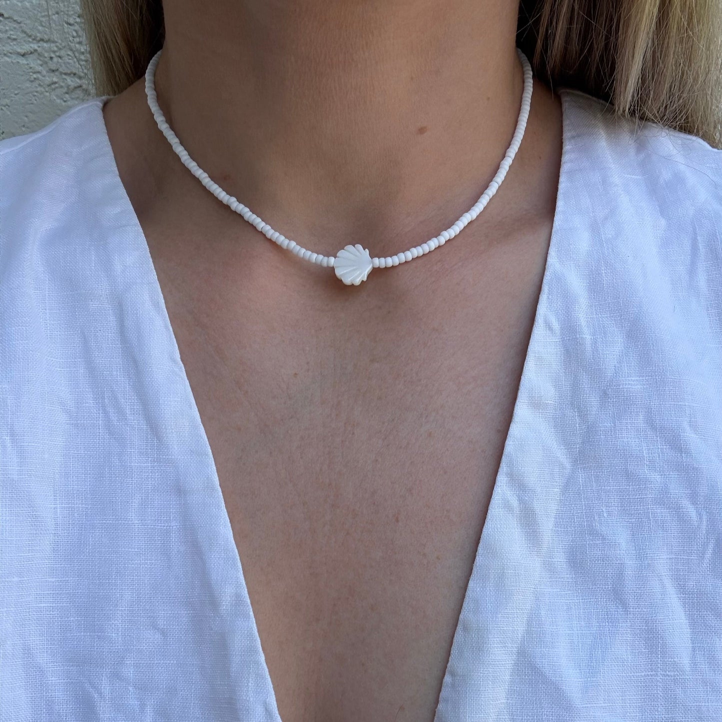 Person wearing a delicate necklace with a white top
