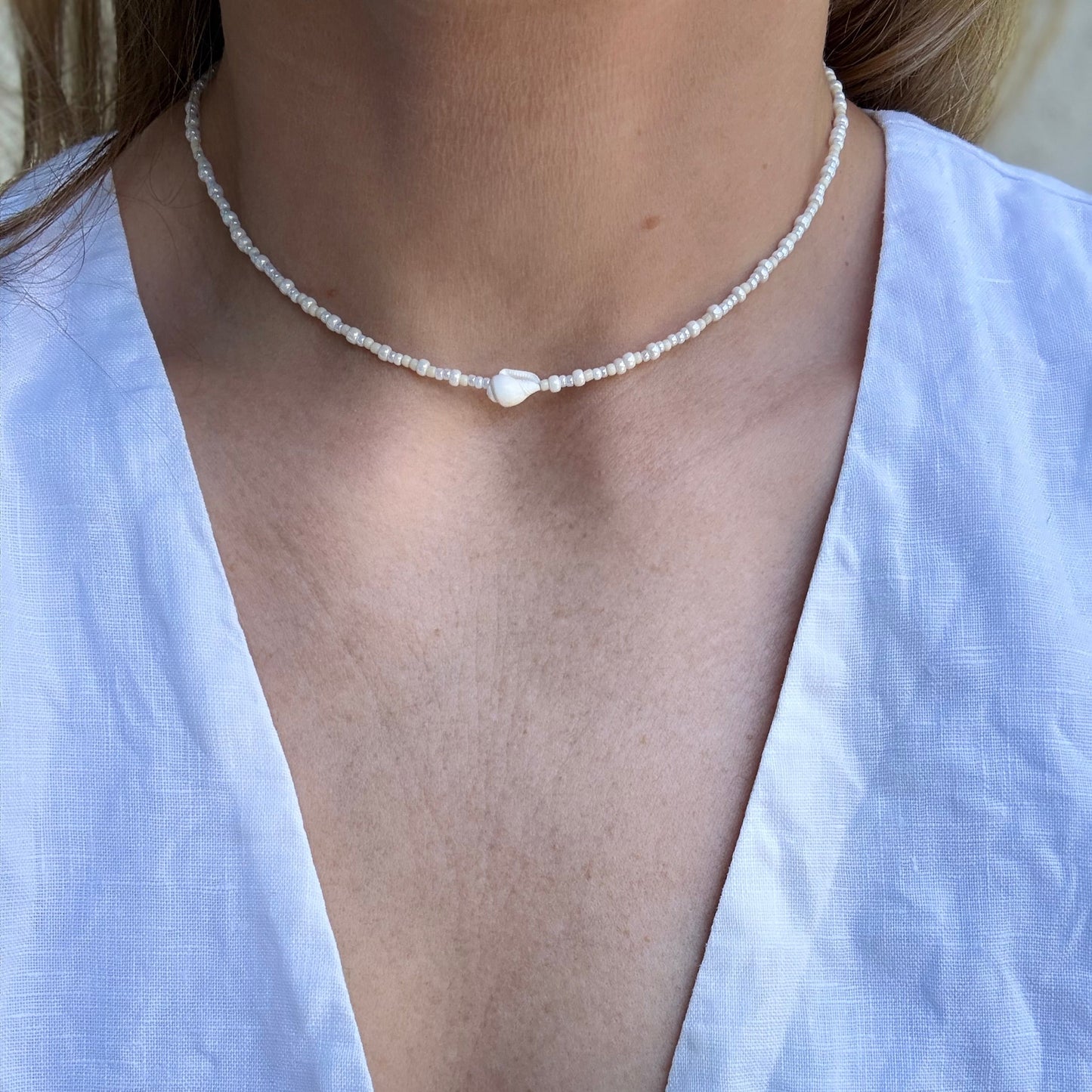 Pearl necklace worn by a person in a white top