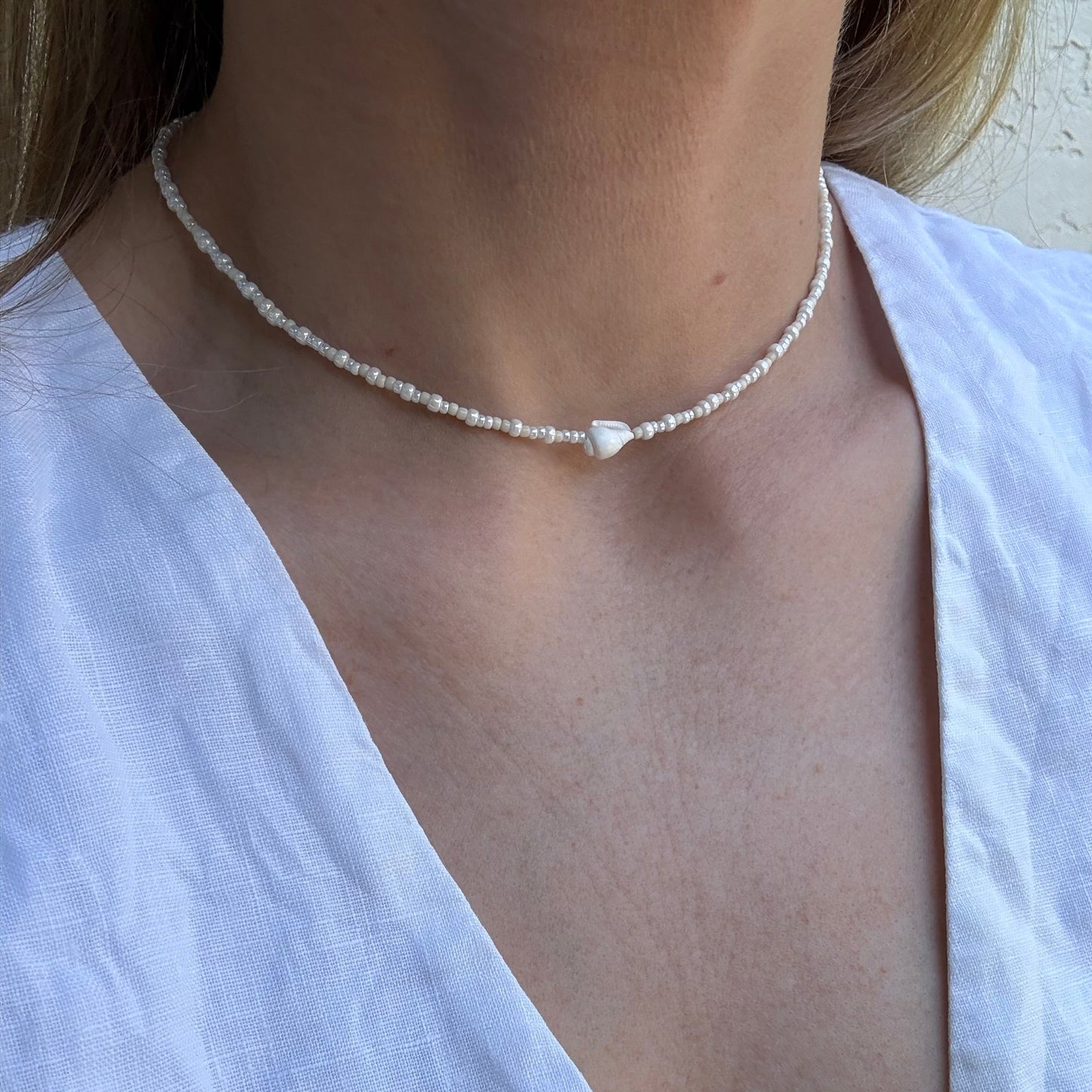 Pearl necklace worn by a person in a white top