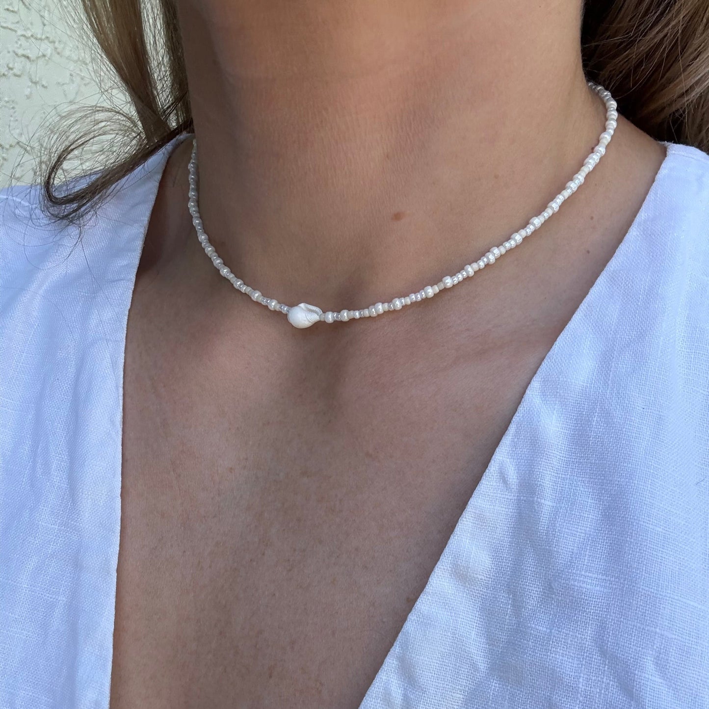 Pearl necklace worn by a person with a white shirt