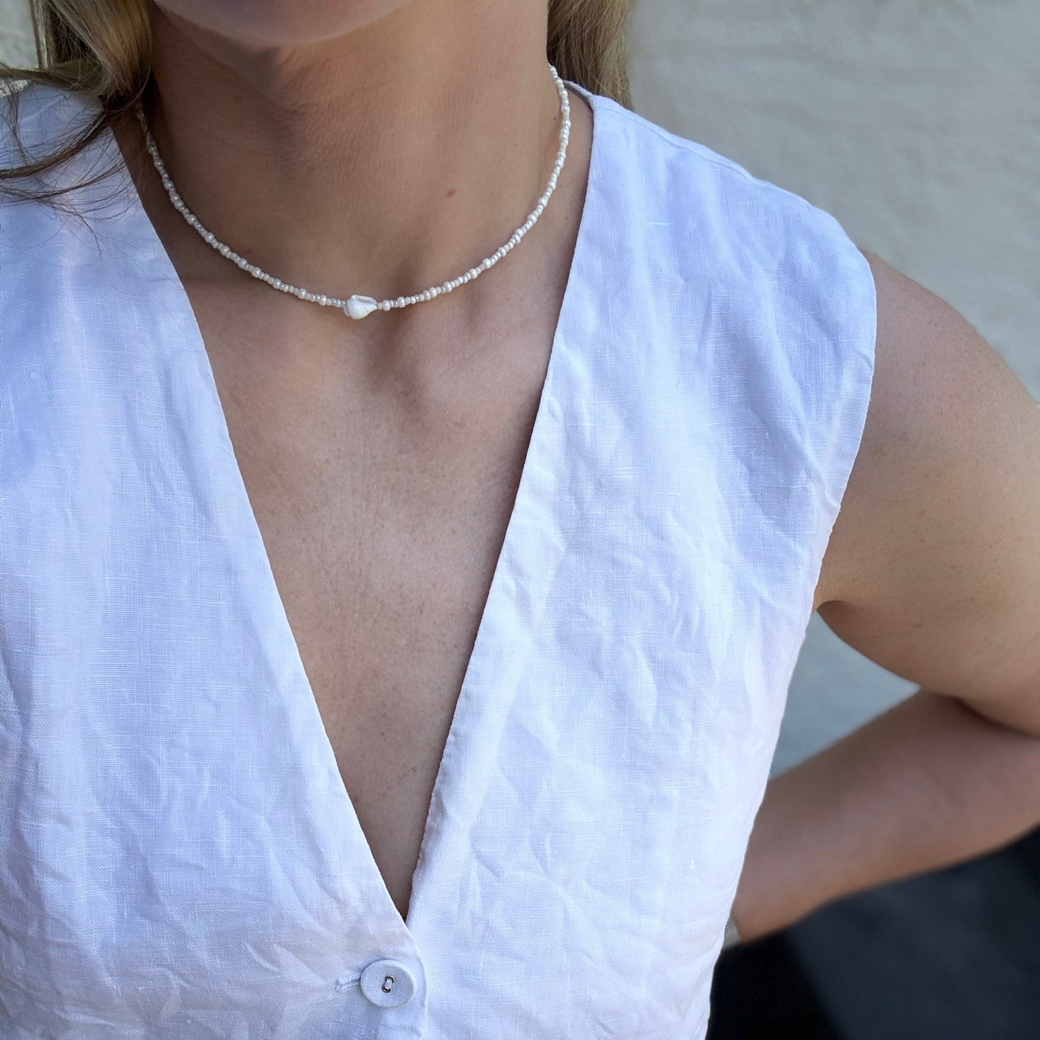 White sleeveless top worn by a person with a blurred background