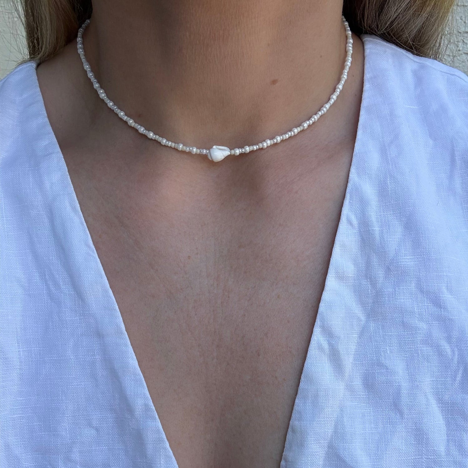Pearl necklace worn by a person in a white top