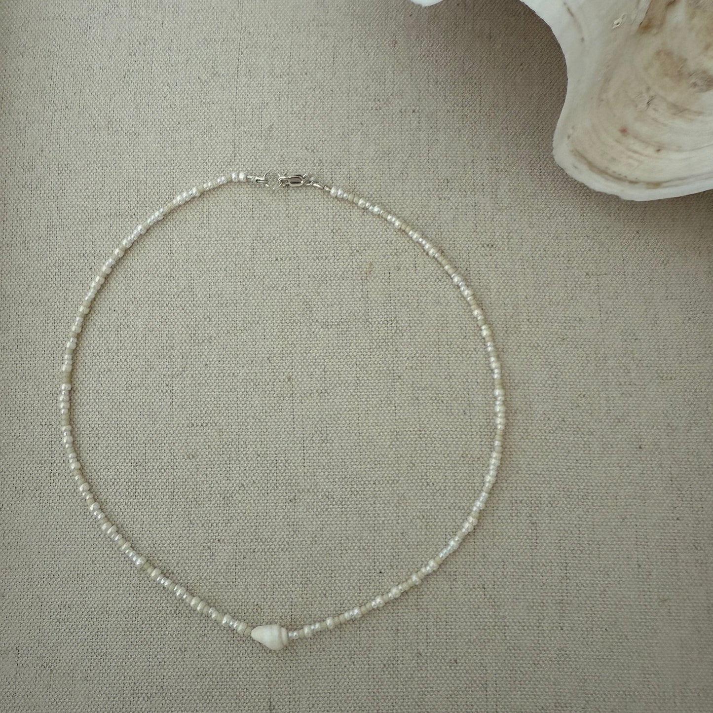 Silver necklace on a textured beige surface