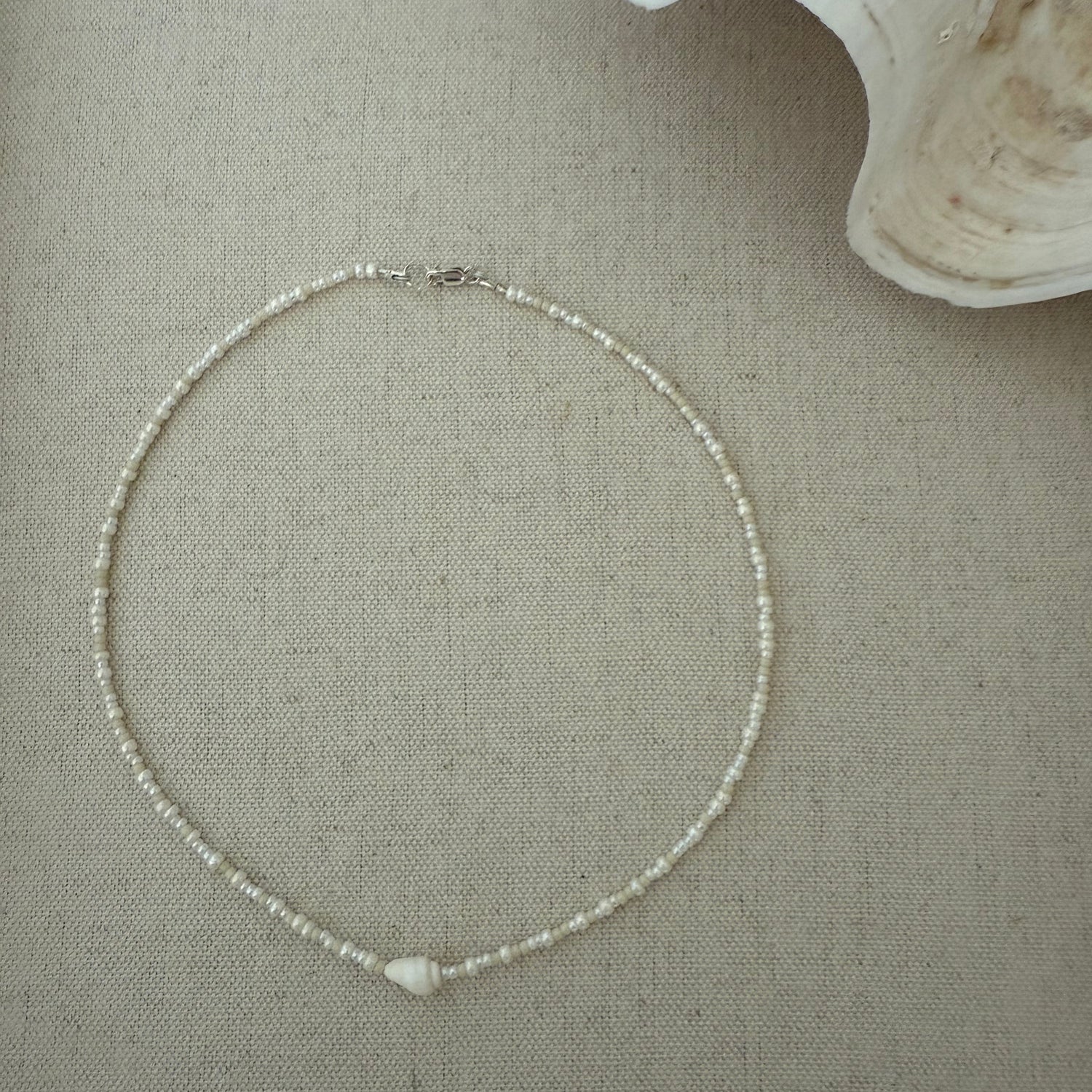 Silver necklace on a textured beige surface