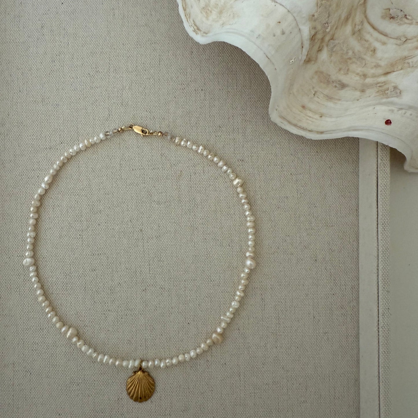Pearl necklace with gold clasp on a textured surface