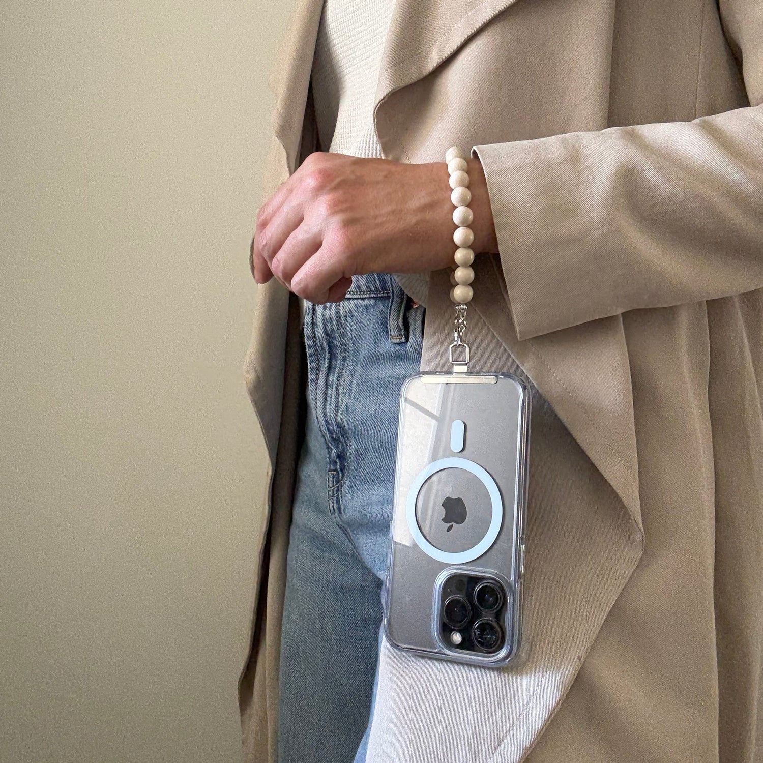 Person holding a phone with a fossil jasper phone chain