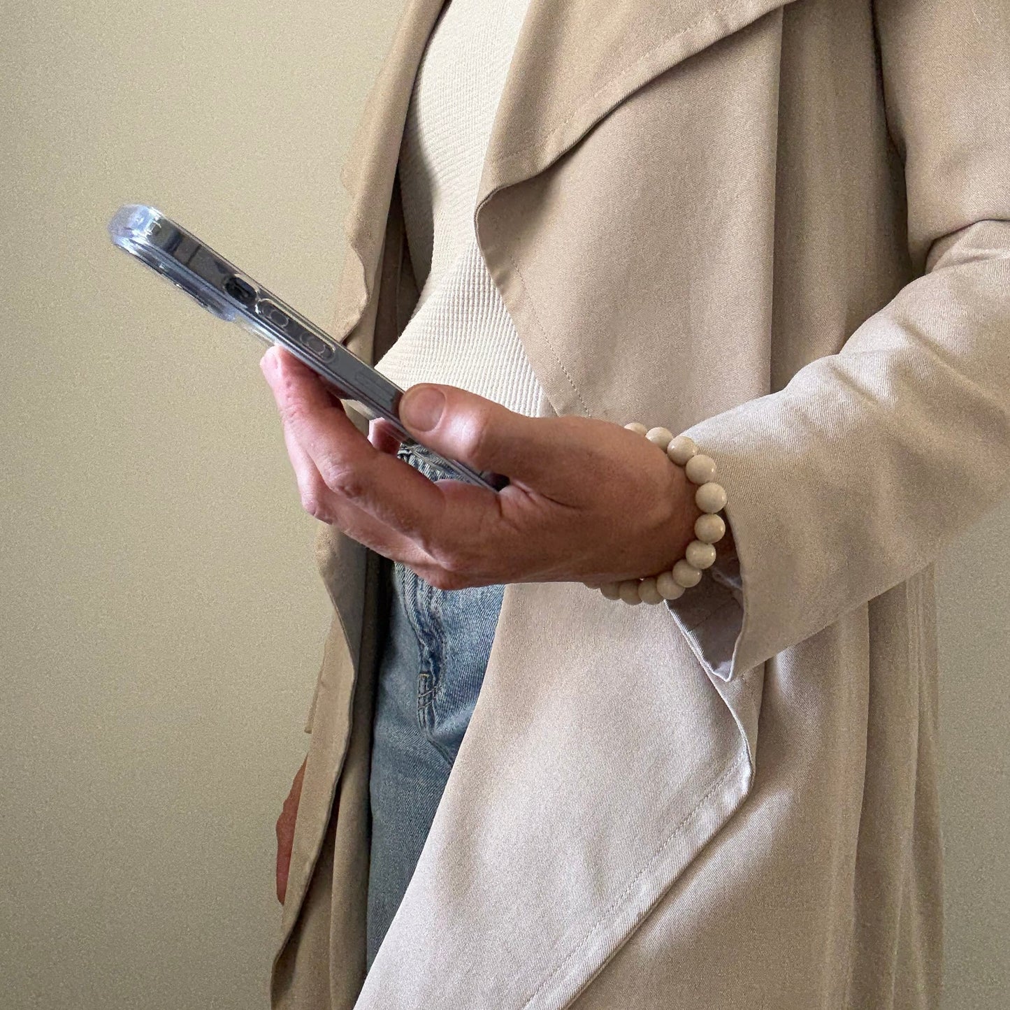 Person holding smartphone with a beaded fossil jasper phone chain