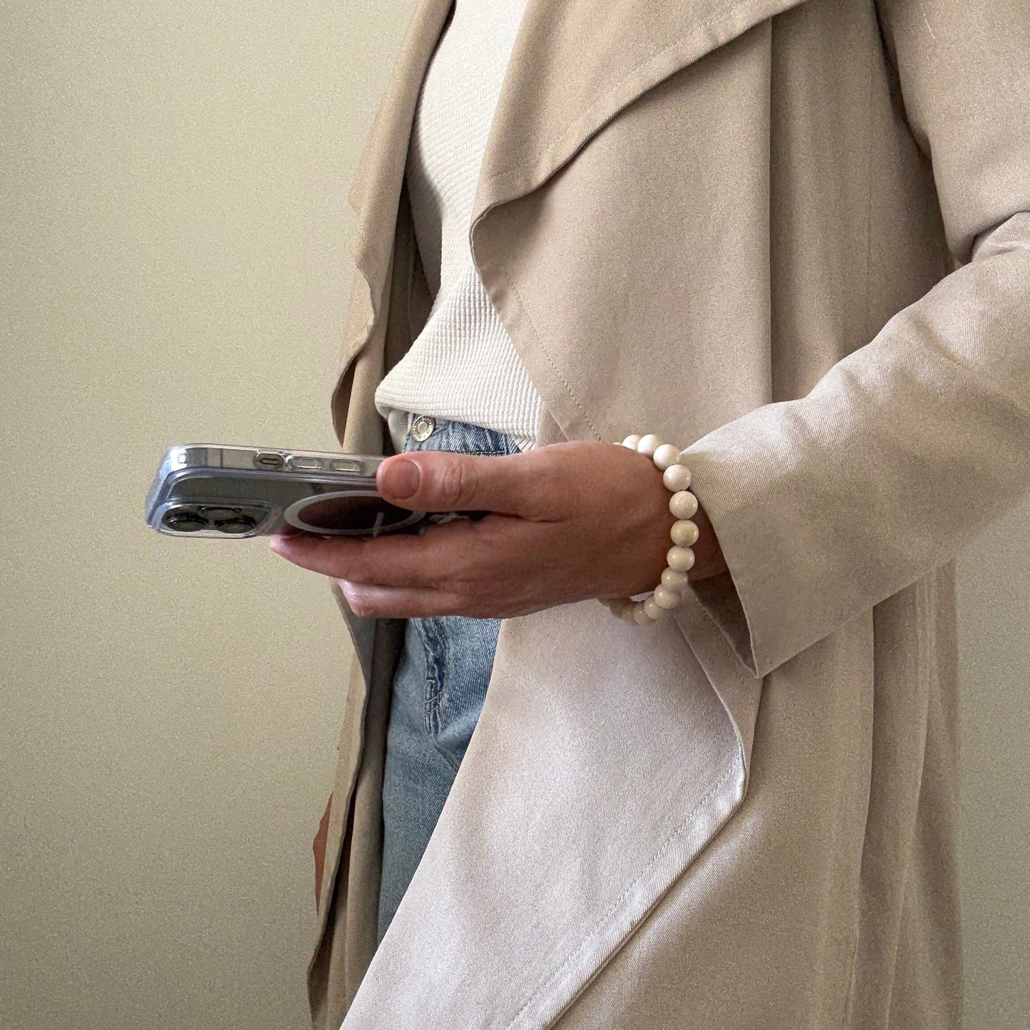 Person holding a smartphone with a fossil jasper phone chain.