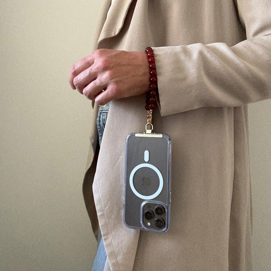 Person wearing a beige coat with a carnelian phone chain on a lanyard against a plain background