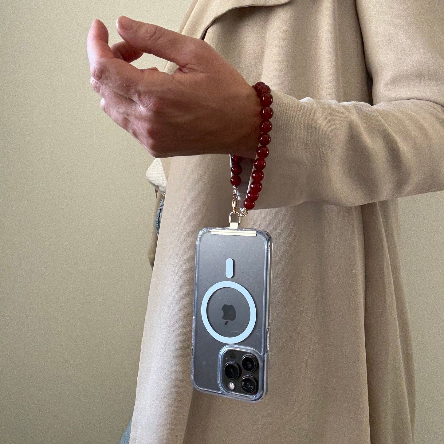 Person holding a phone with a carnelian phone chain.