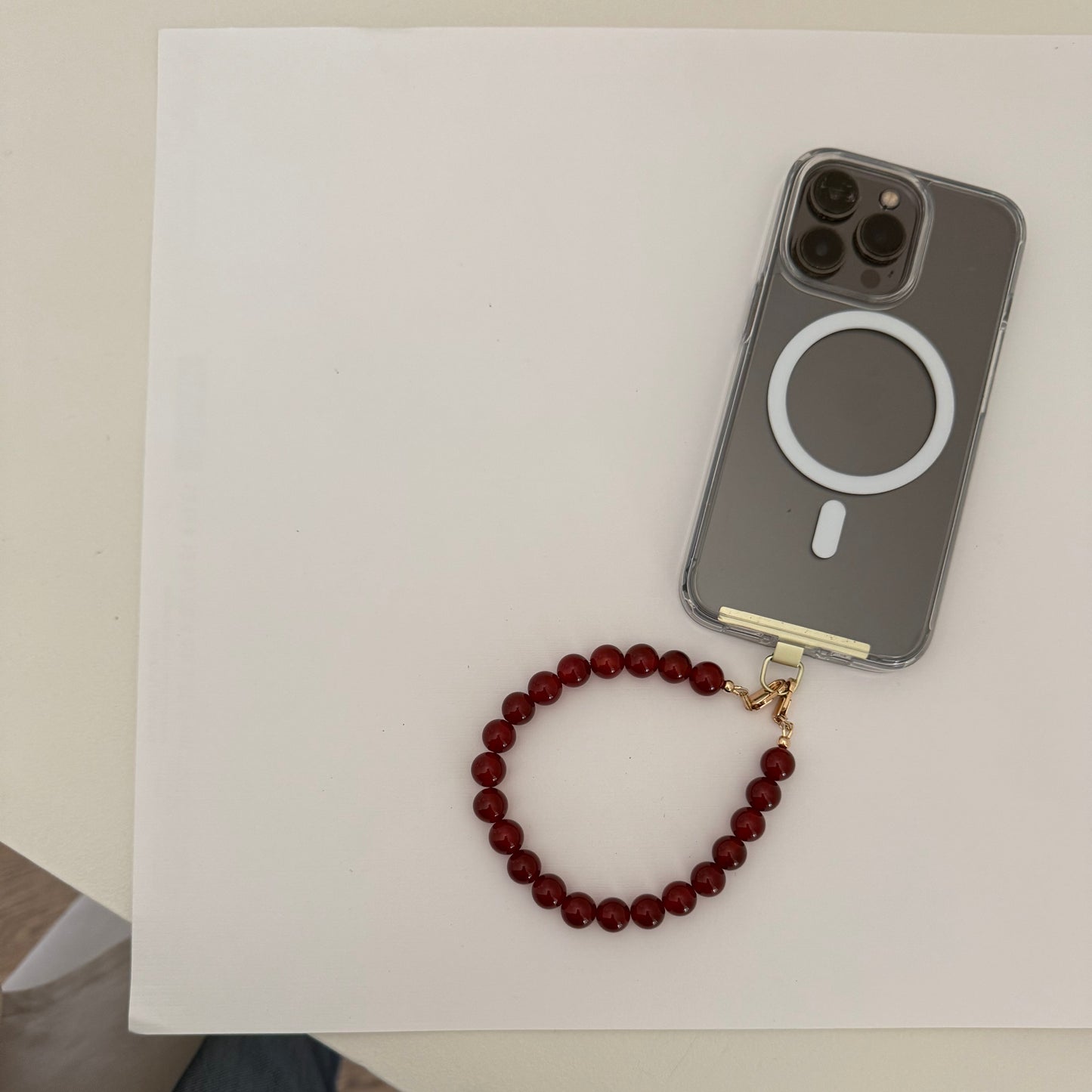 Phone case with a beaded carnelian phone chain on a white surface