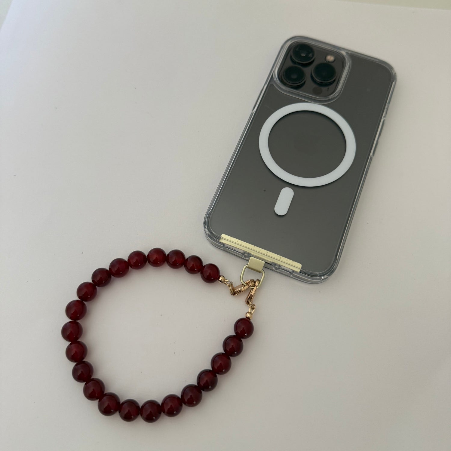 Phone case with a red beaded phone chain on a white surface