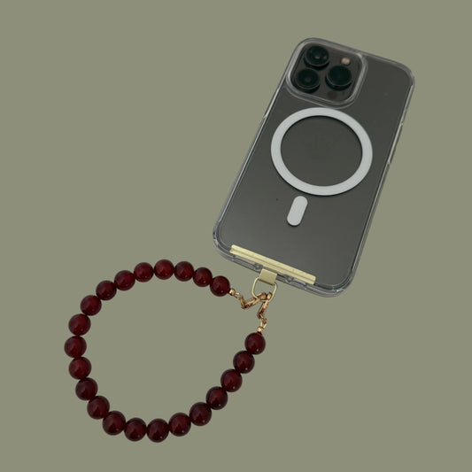Phone case with a red beaded phone chain on a white surface