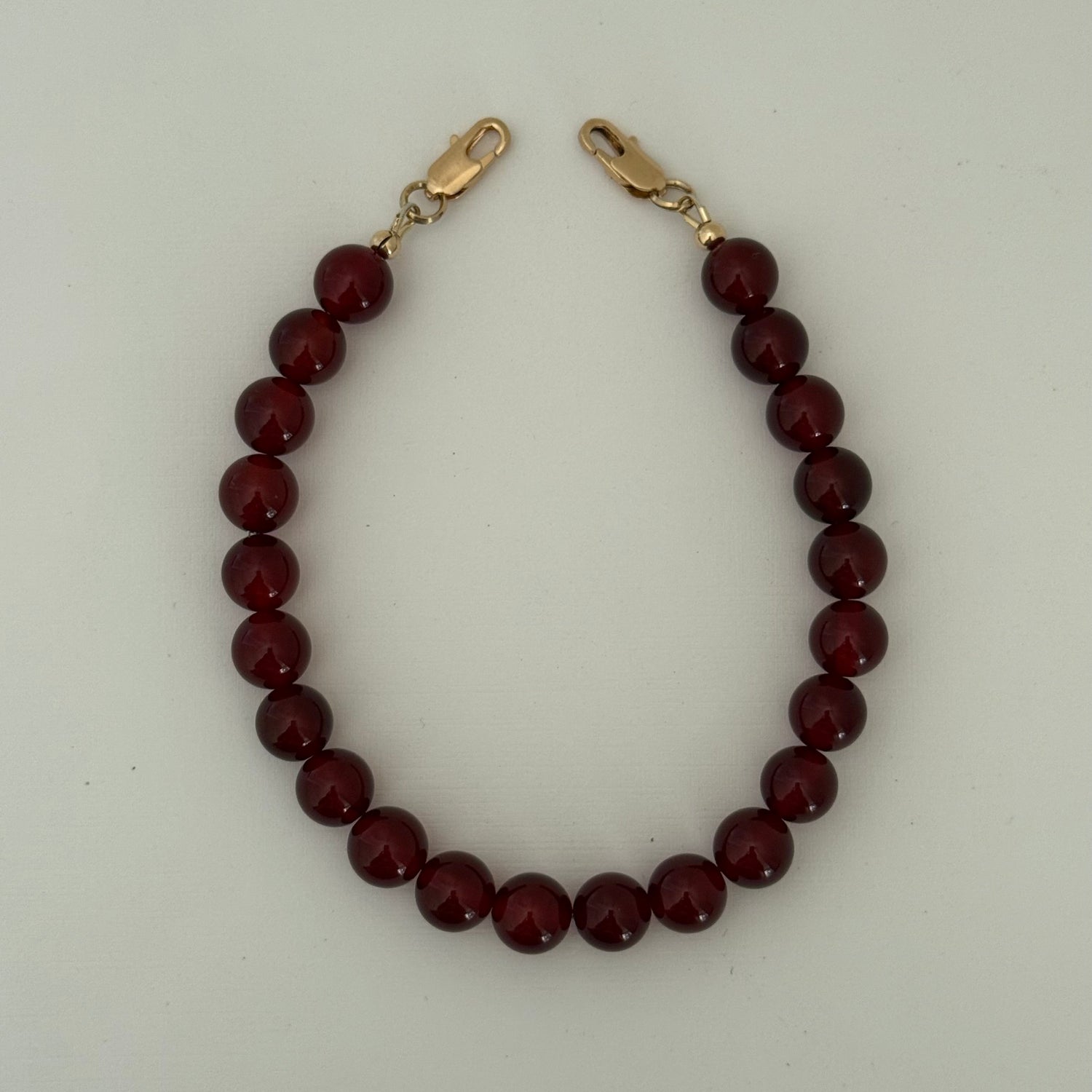 Beaded carnelian phone chain with gold clasps on a light gray background