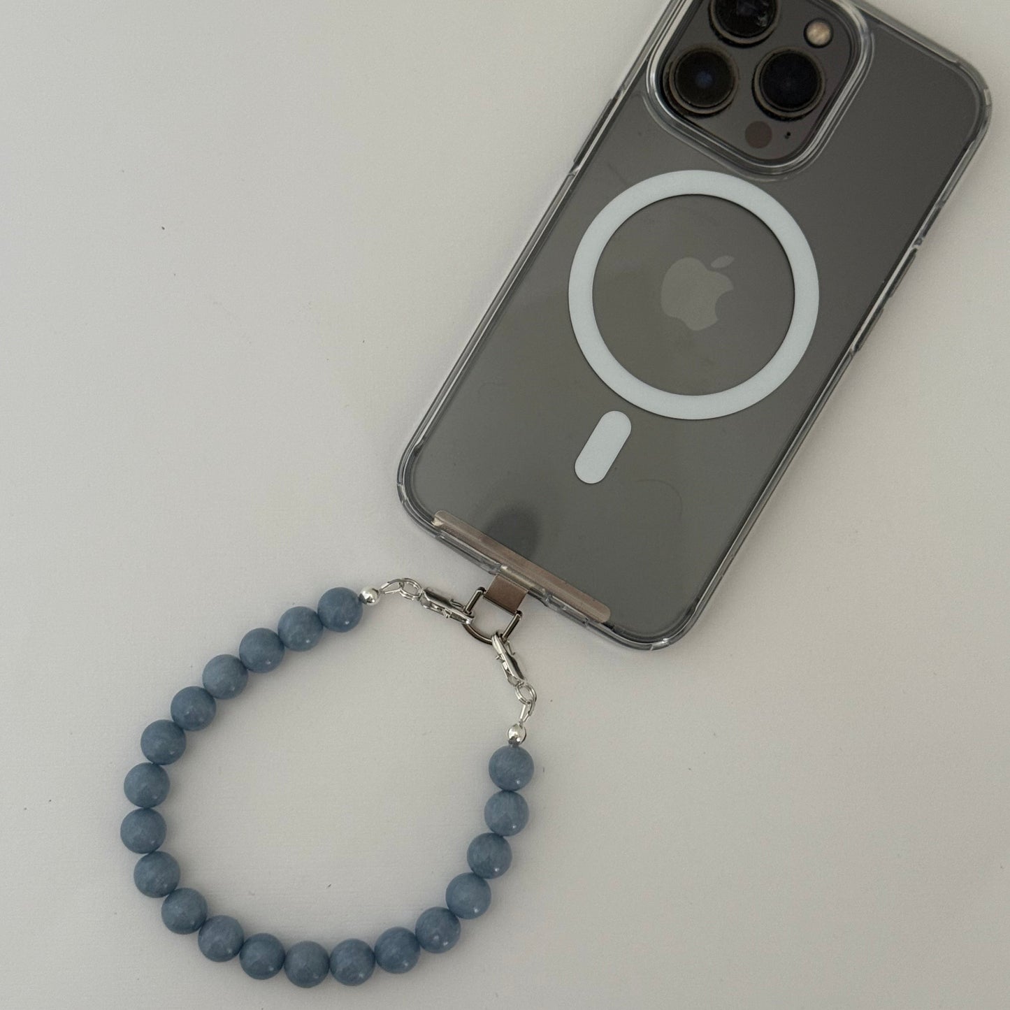 Smartphone with a blue beaded phone chain on a light gray background