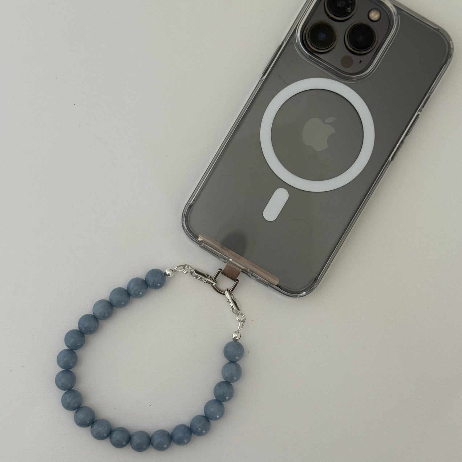 Smartphone with a blue beaded phone chain on a light gray background