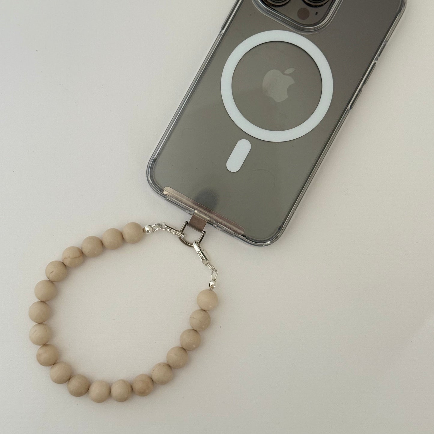 Phone case with Apple logo and beaded fossil jasper phone chain on a white background
