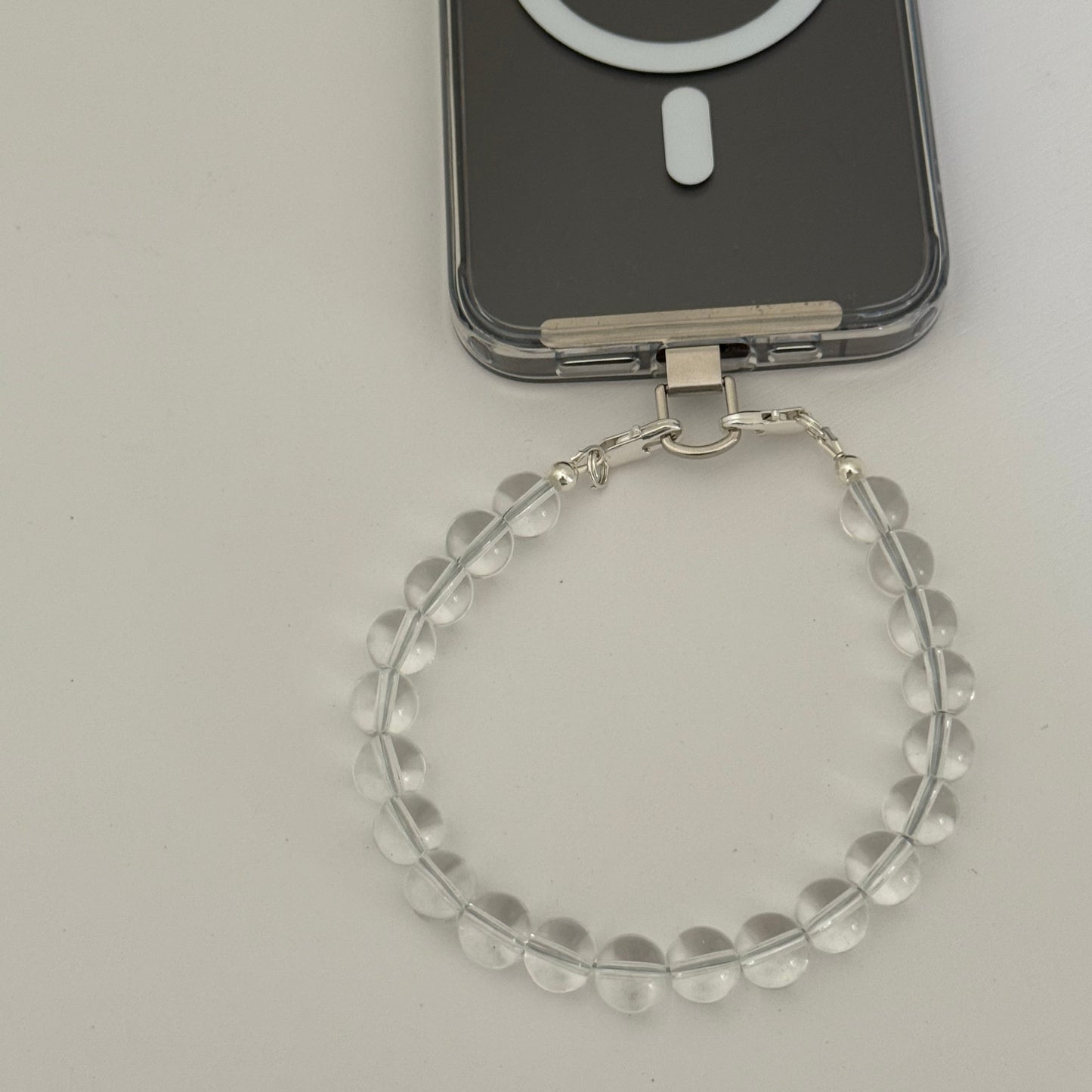 Smartphone with beaded clear quartz crystal phone chain on a light gray background