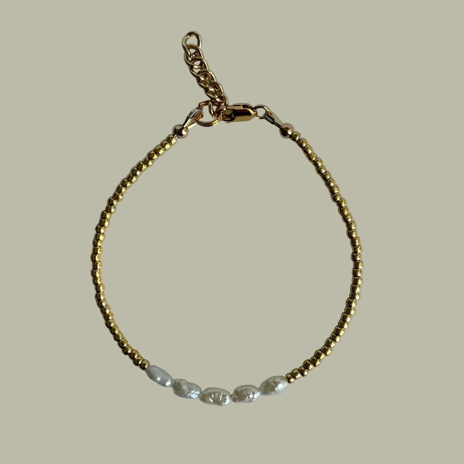 Gold bracelet on a light gray background