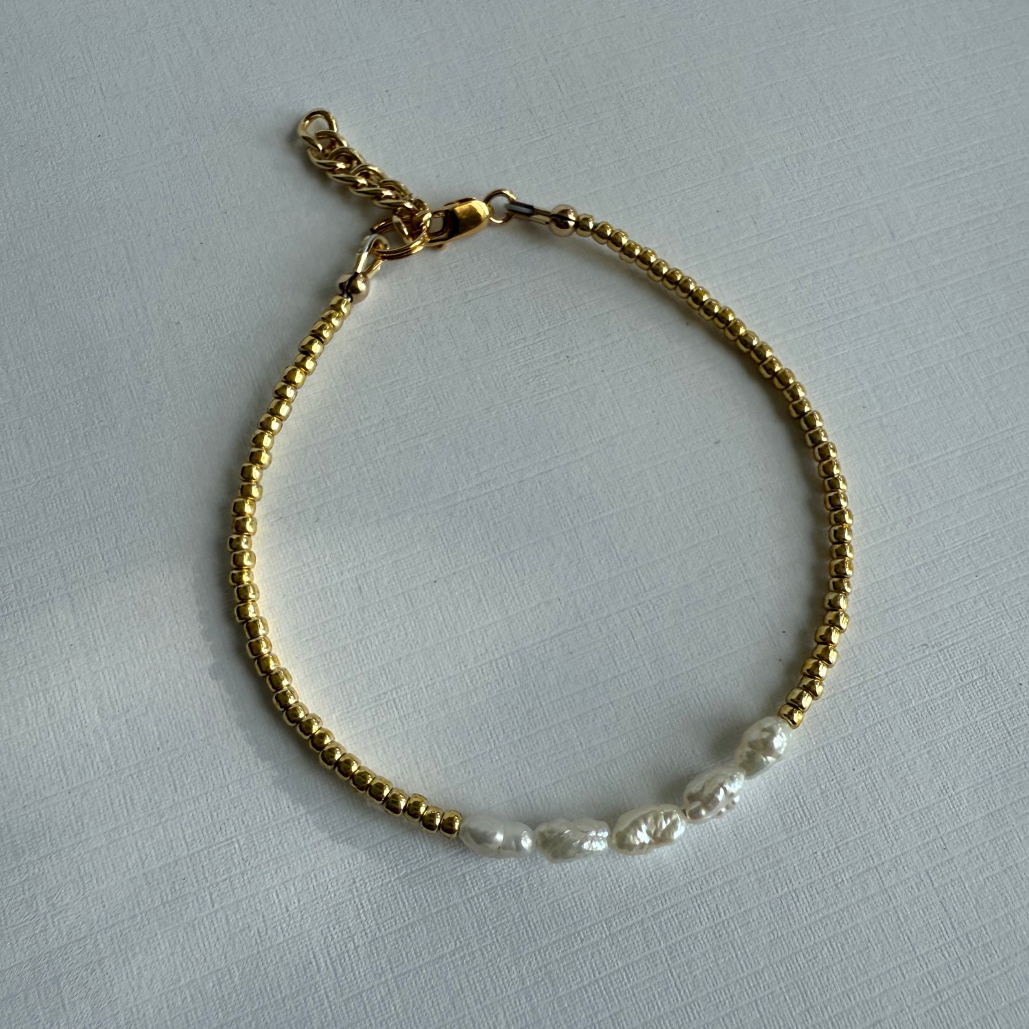 Gold bracelet with pearls on a gray background