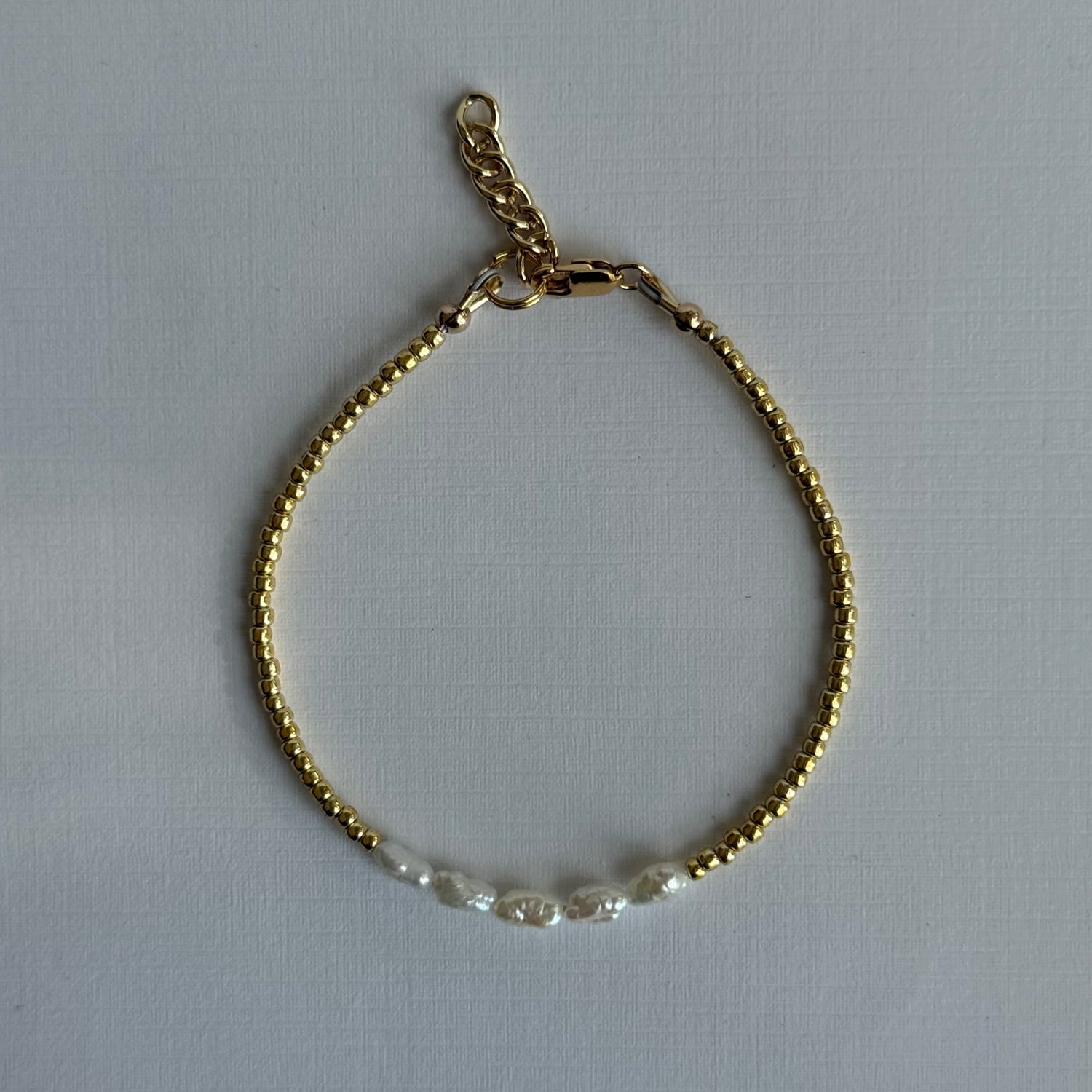Gold bracelet with a chain on a light gray background