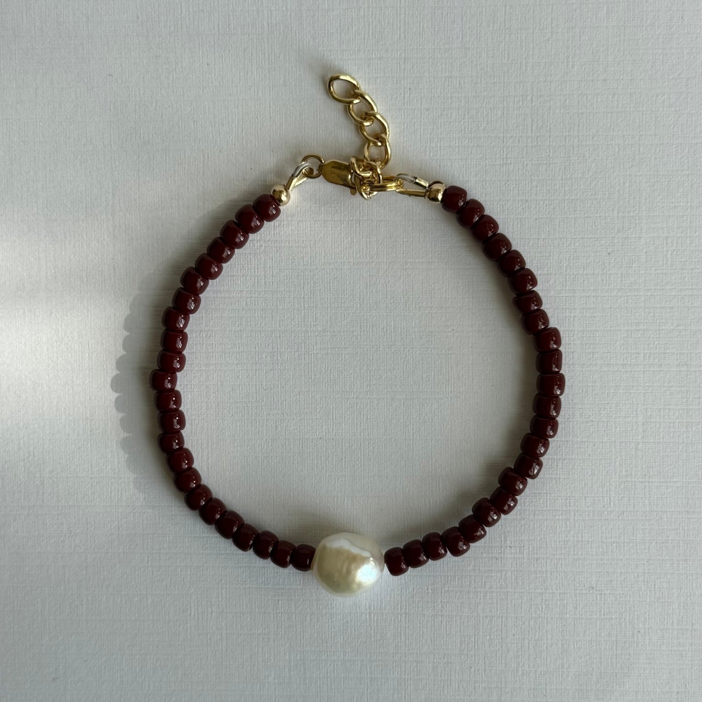 Bracelet with brown beads and a pearl on a light gray background