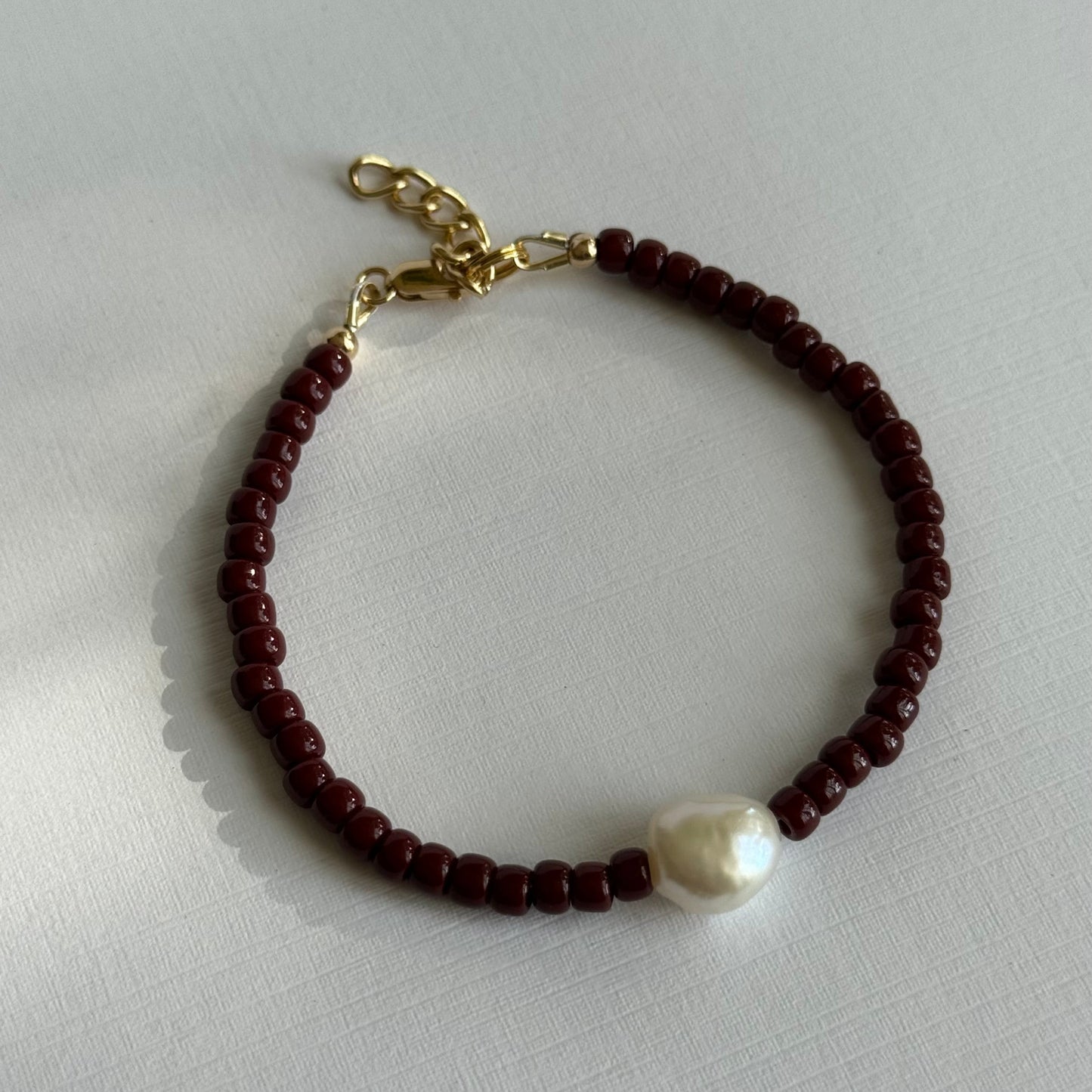 Bracelet with brown beads and a pearl on a light gray background