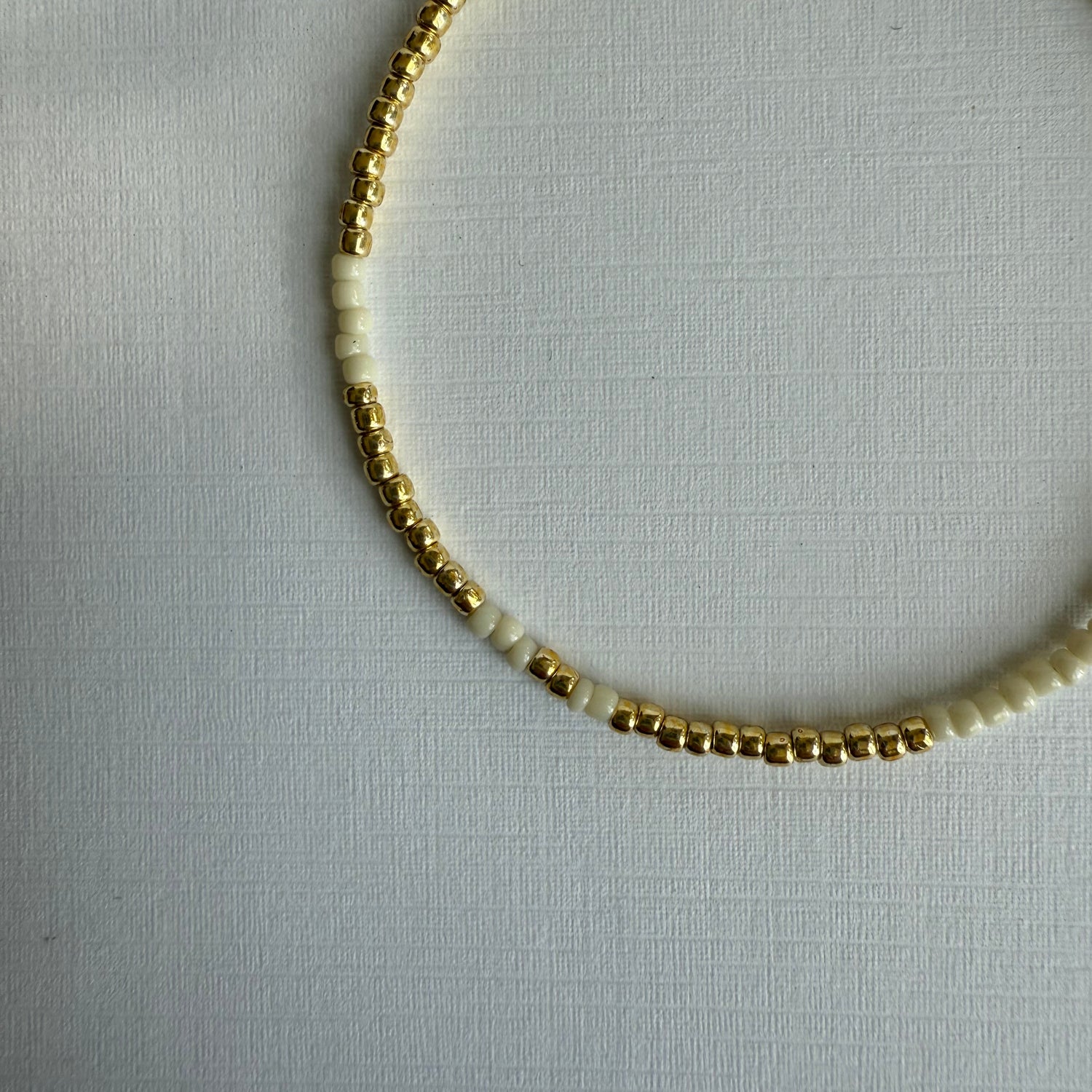 Necklace with gold and white beads on a light gray background