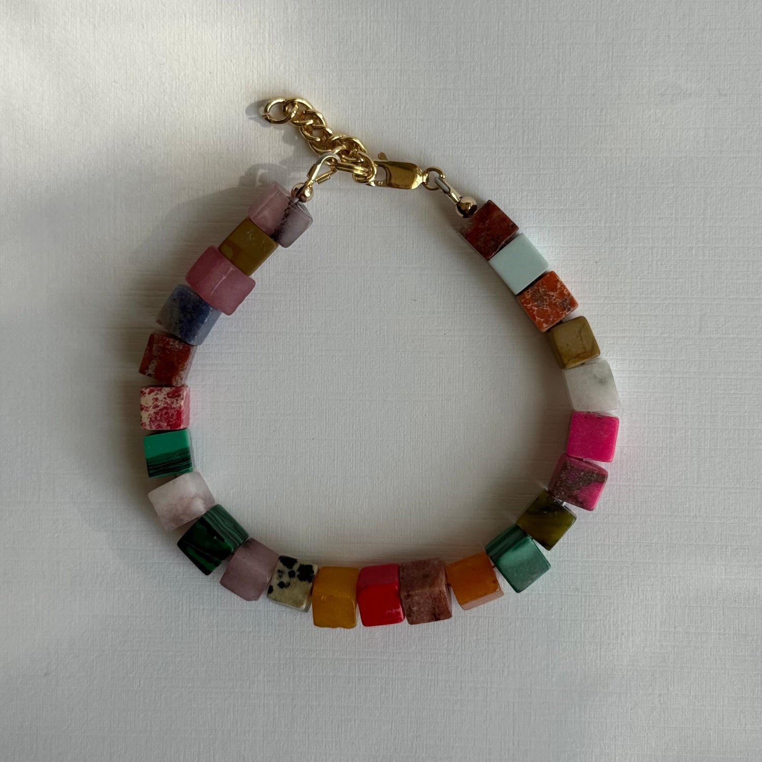 Multicolored beaded bracelet with a gold chain on a white background