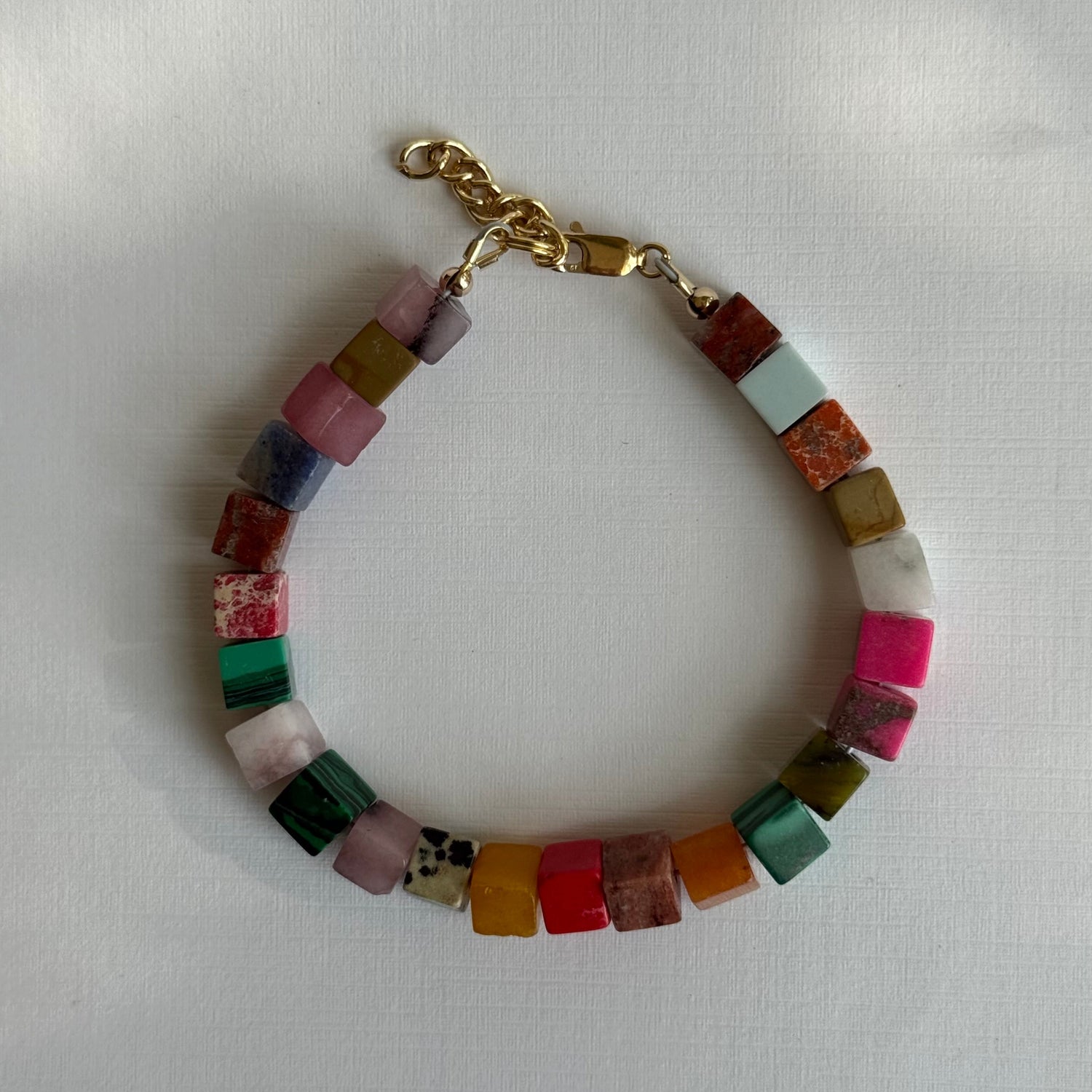 Multicolored beaded bracelet with gold clasp on a white background