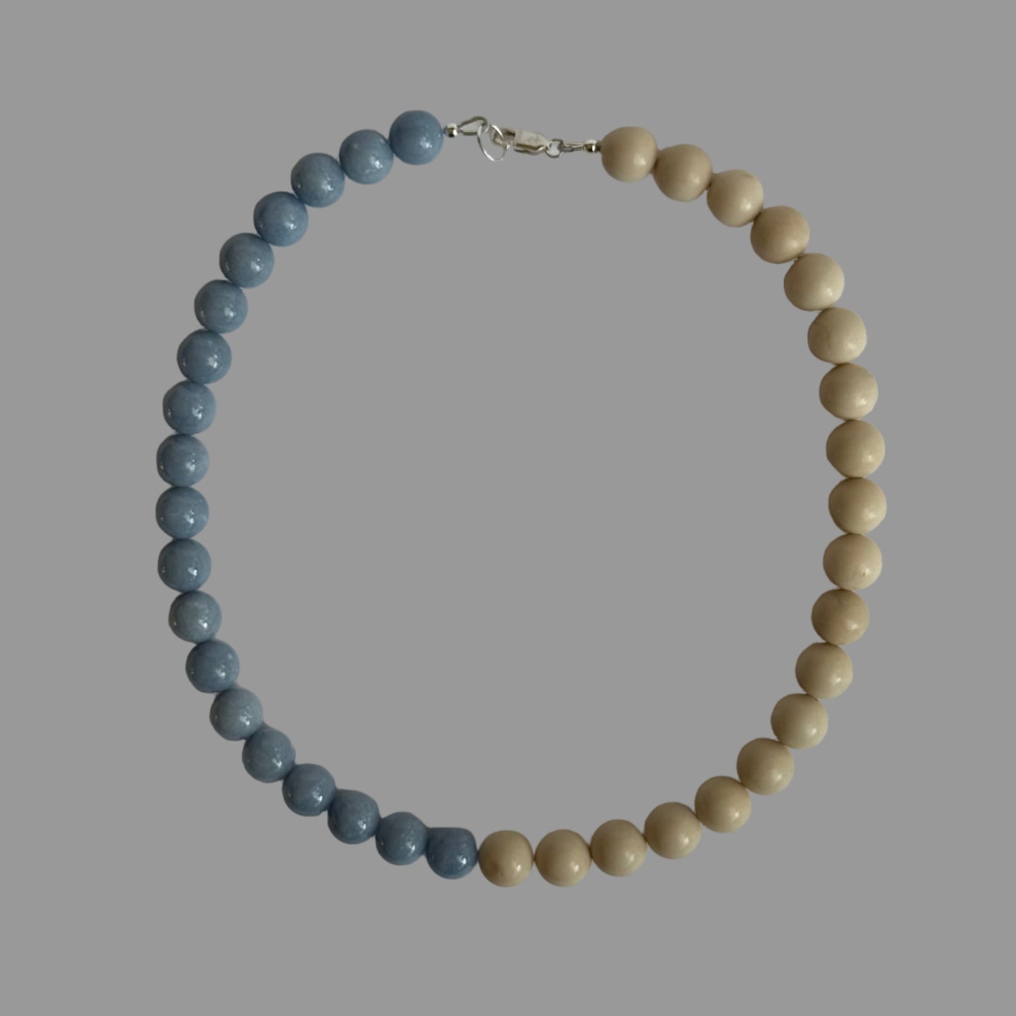 Beaded necklace with blue and beige beads on a light gray background