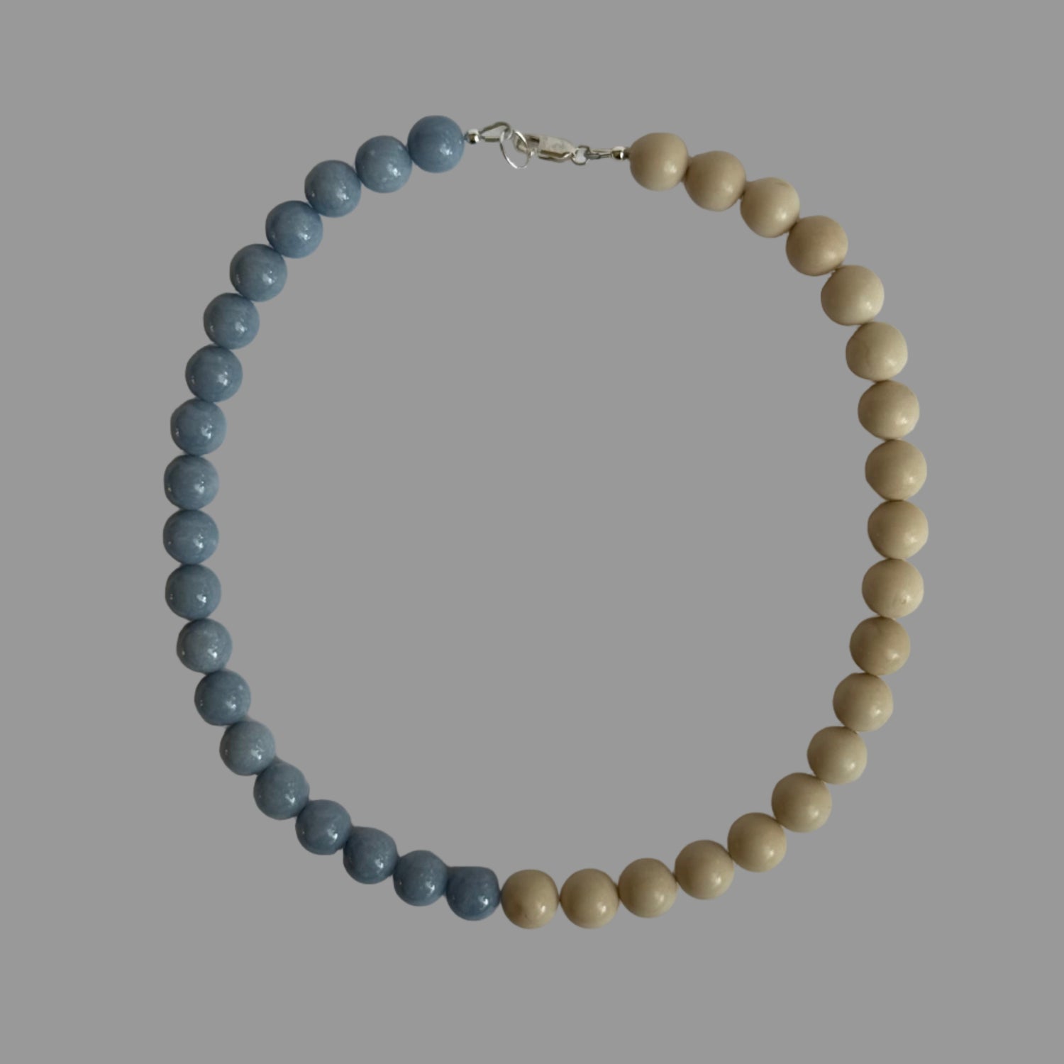 Beaded necklace with blue and beige beads on a light gray background