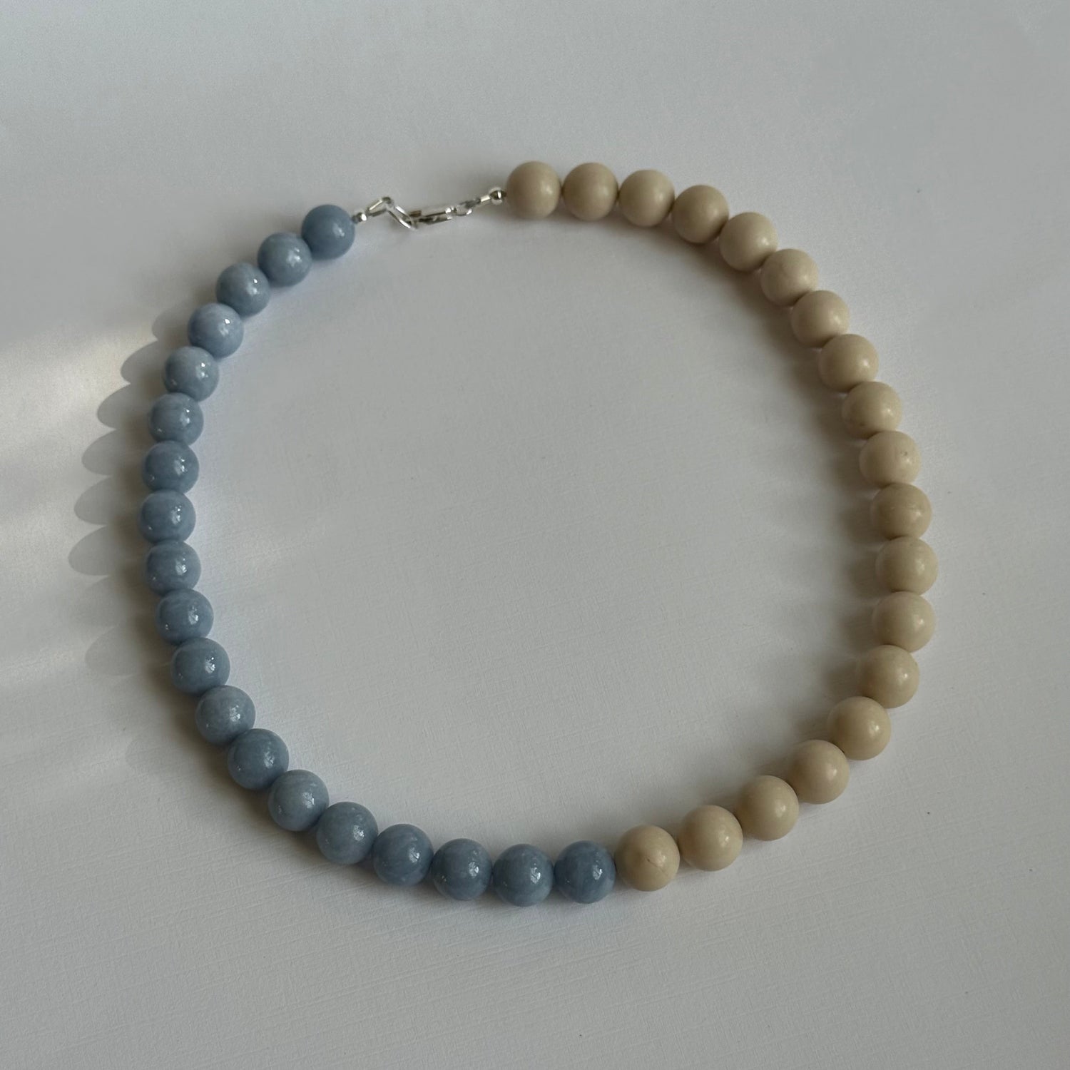 Necklace with blue and beige beads on a white surface