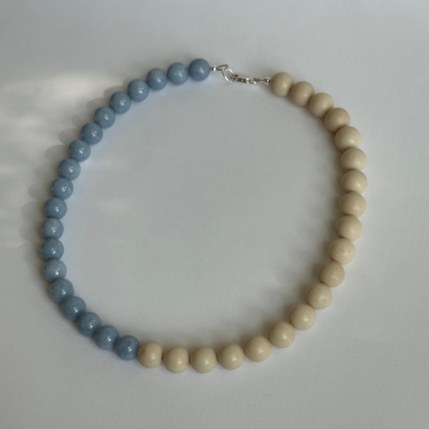 Necklace with blue and beige beads on a light gray background