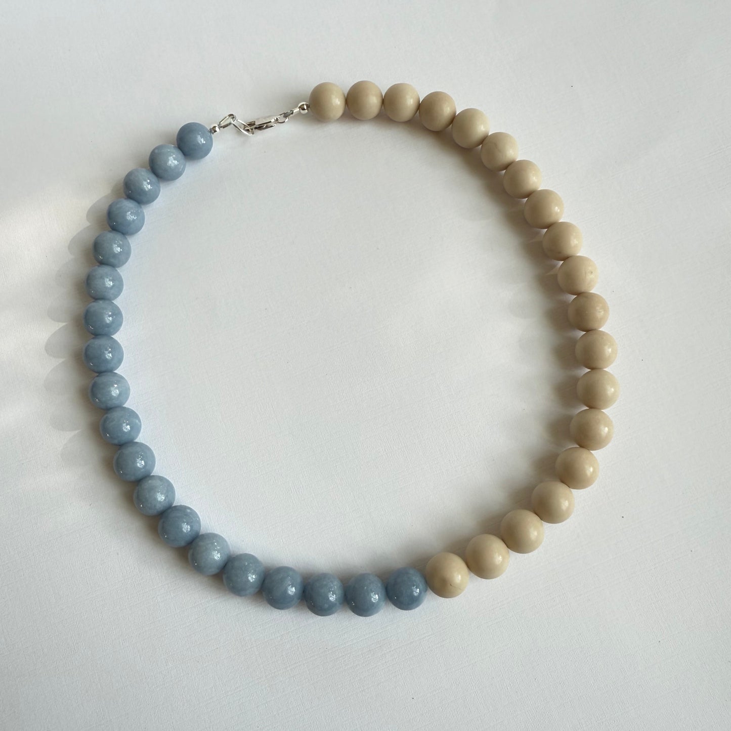 Necklace with alternating light wood and blue beads on a white background