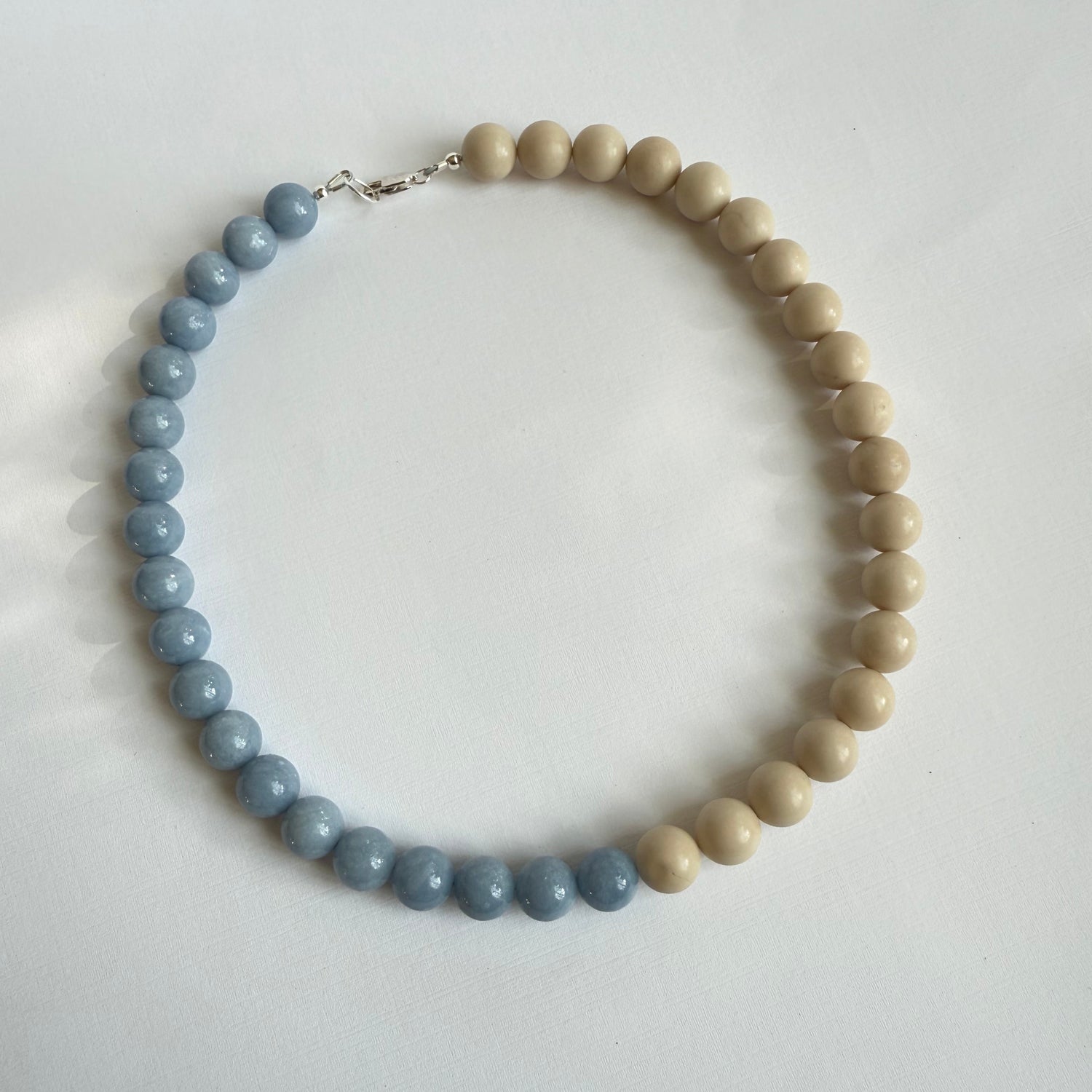 Necklace with alternating light wood and blue beads on a white background