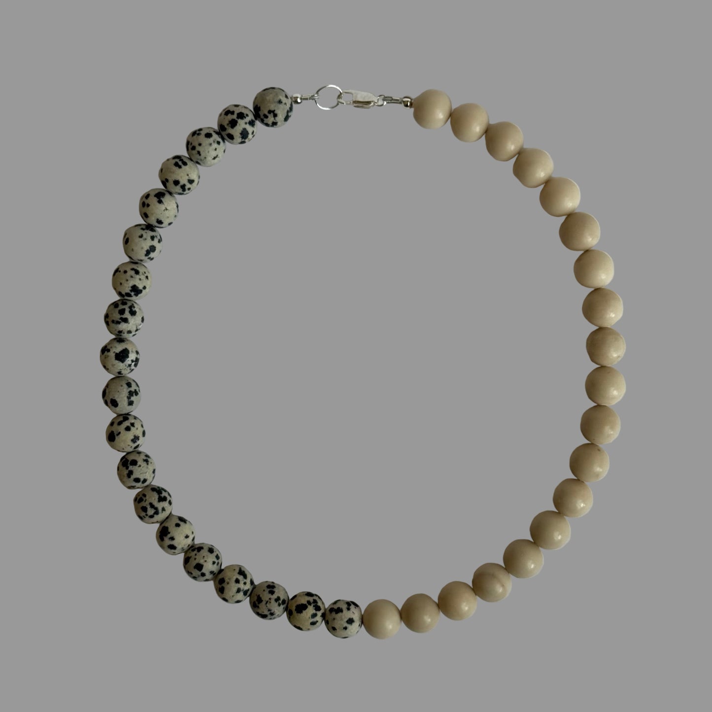 Necklace with alternating black and white beads on a light gray background